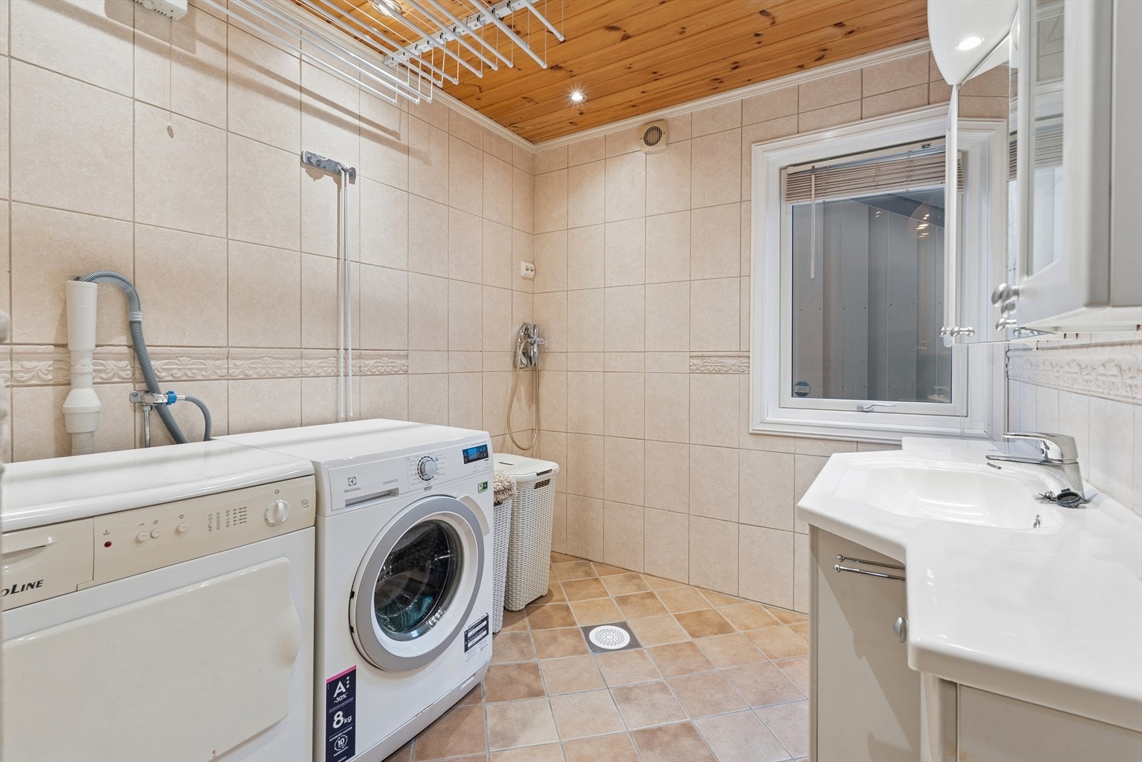 Vaskerommet er helfliset med lyse fliser på gulv og vegger. I gulvet har man også varmekabler for ekstra komfort. Vaskerommet er ellers utstyrt med baderomsinnredning med nedfelt servant, dusjarmatur og opplegg for vaskemaskin. Galleribilde