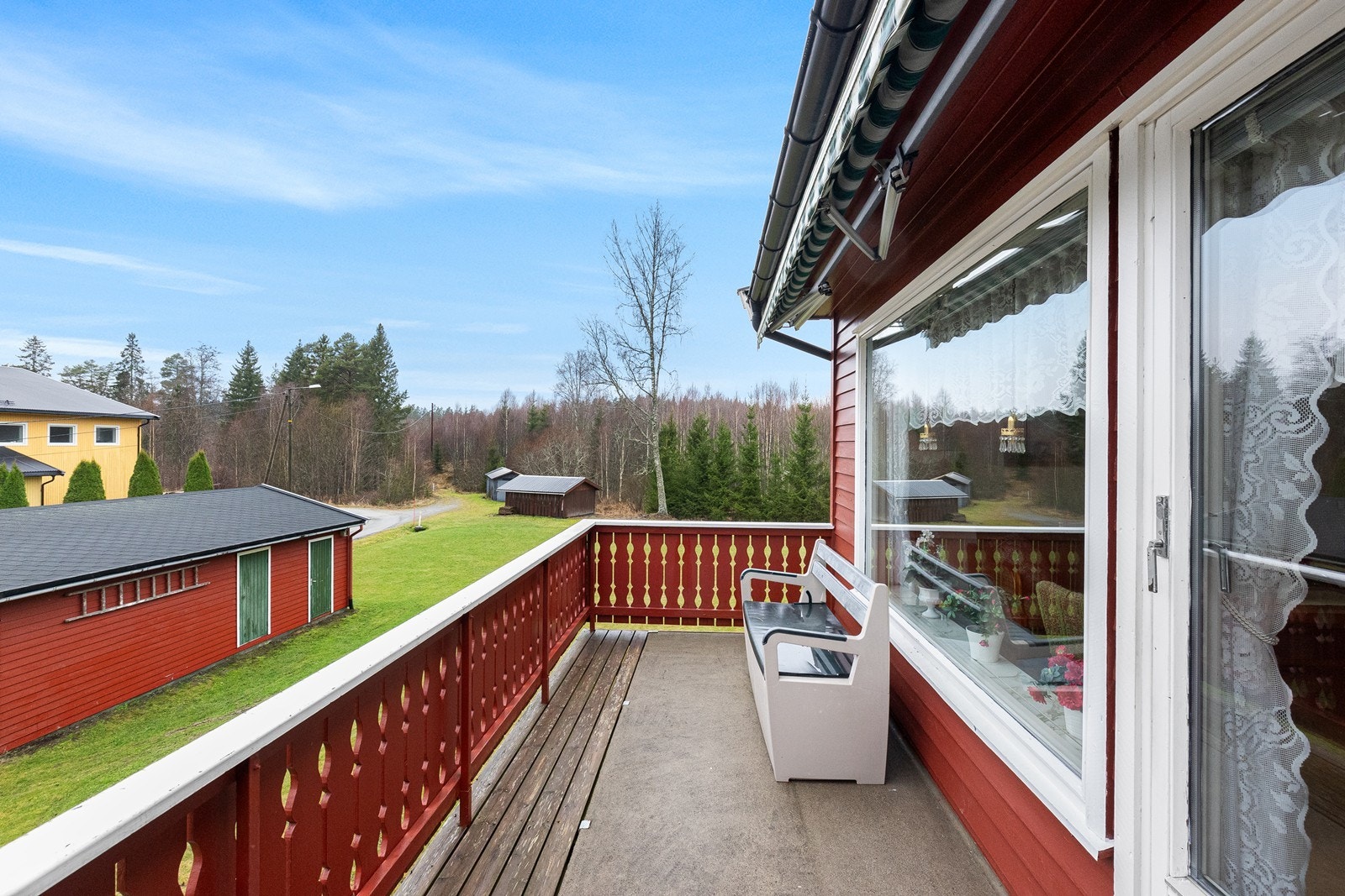 Verandaen er utstyrt med malt trevirke på rekkverket og har en markise montert. Galleribilde