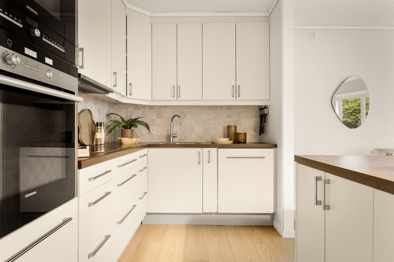 Kjøkkenet har lyse tidløse fronter med en lun trefarget benkeplate i laminat Galleribilde