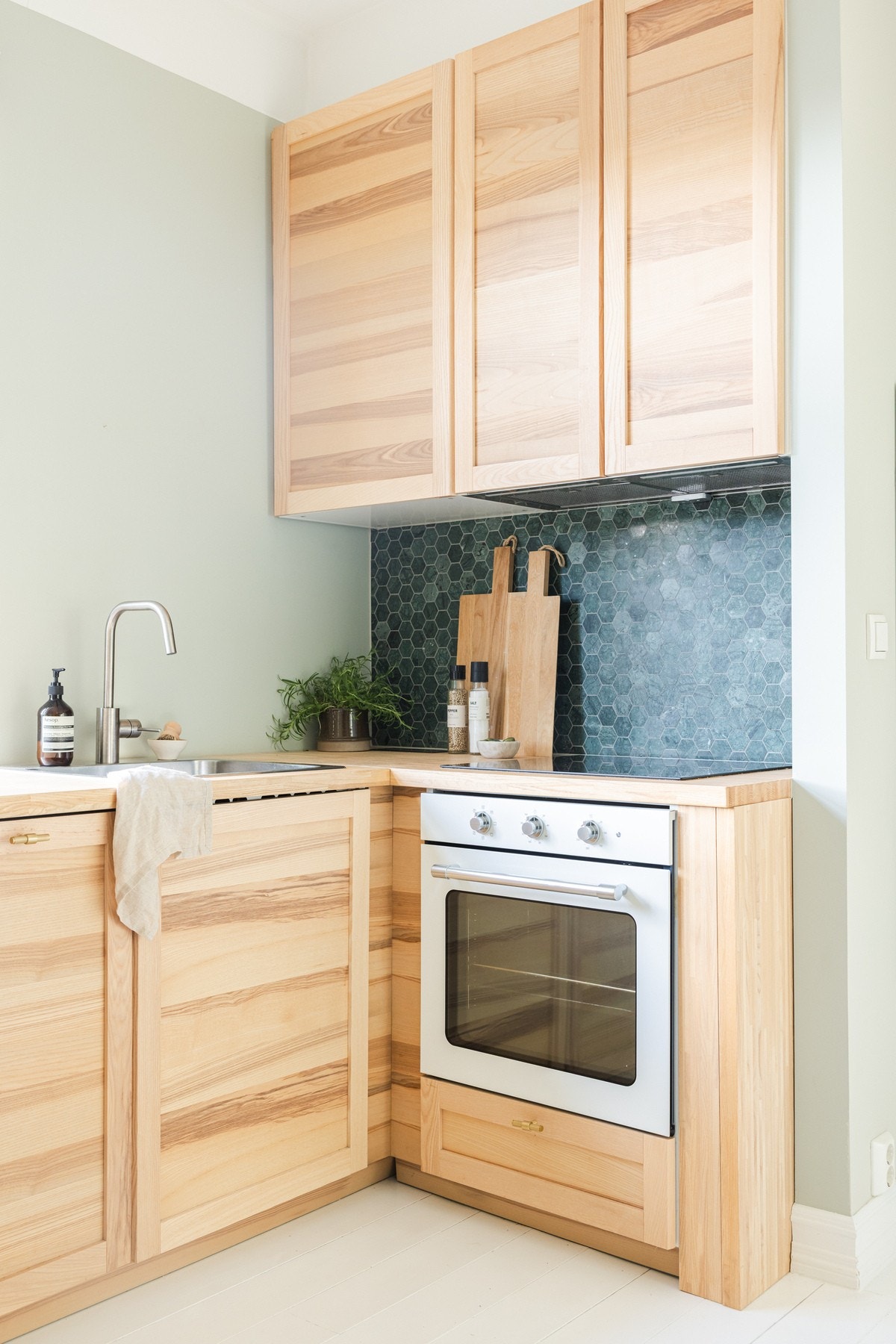 Vider har kjøkkenet ventilator over platetopp, nedfelt oppvaskkum og dekorative mosaikkfliver på vegg over benk Galleribilde