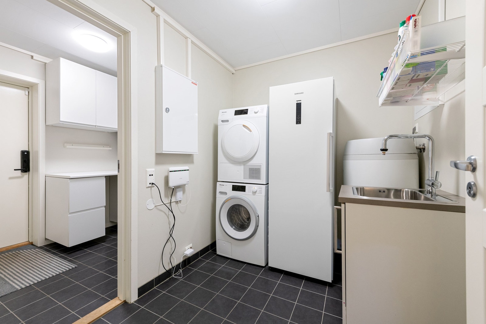 Vaskerom og bod med dør til markterrasse/hage og utestue Galleribilde