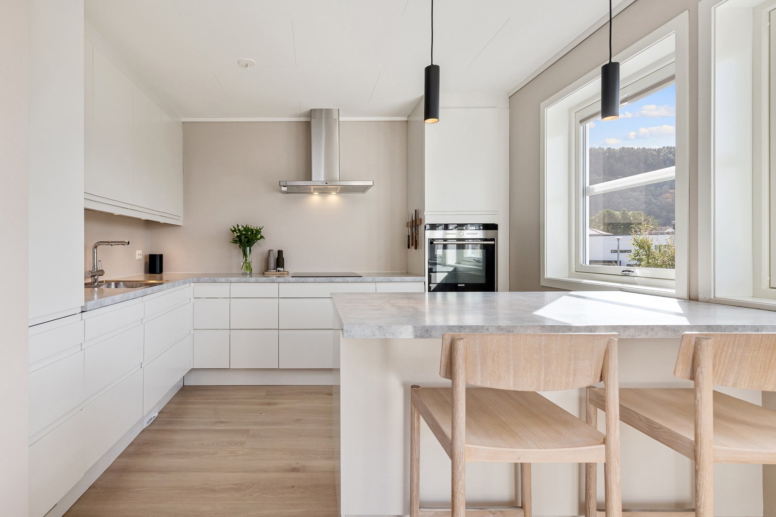 Kjøkkenet har innredning fra HTH med hvite glatte fronter og benkeplaten er av laminat. Det er varme i gulv, flott belysning, tilpasset solskjerming i vinduer Galleribilde