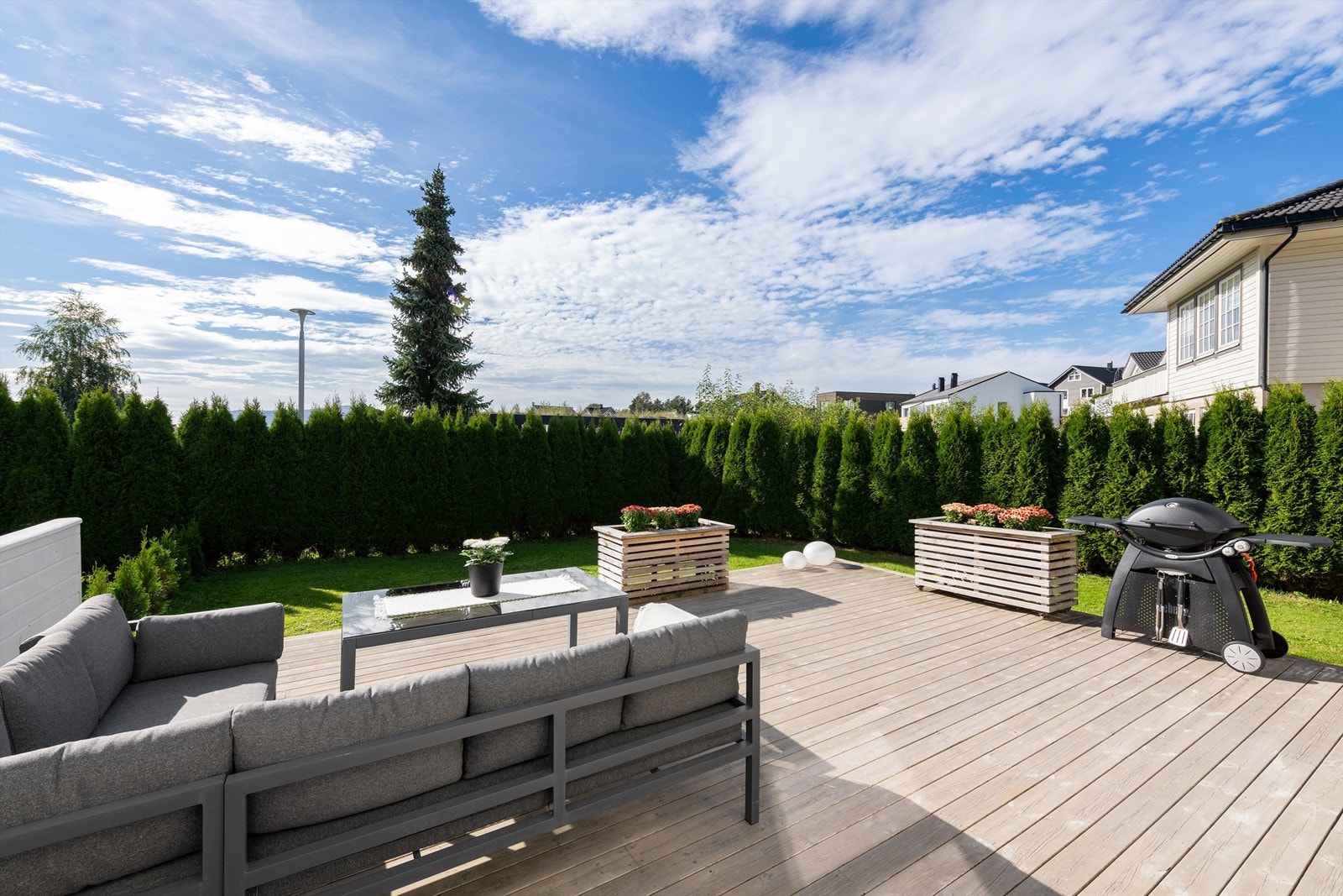 Lett adkomst fra terrassen til hage som er skjermet og inngjerdet med hekk Galleribilde