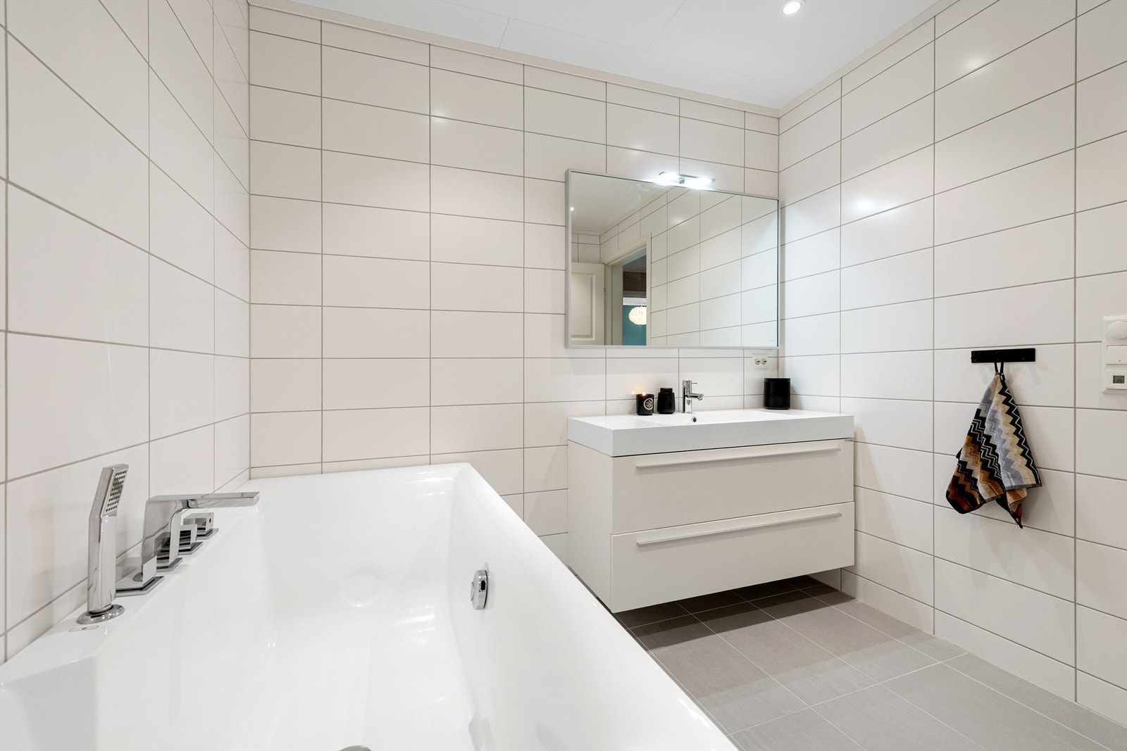 Flott flislagt bad i underetasjen med innredning, speil, wc og frittstående badekar Galleribilde