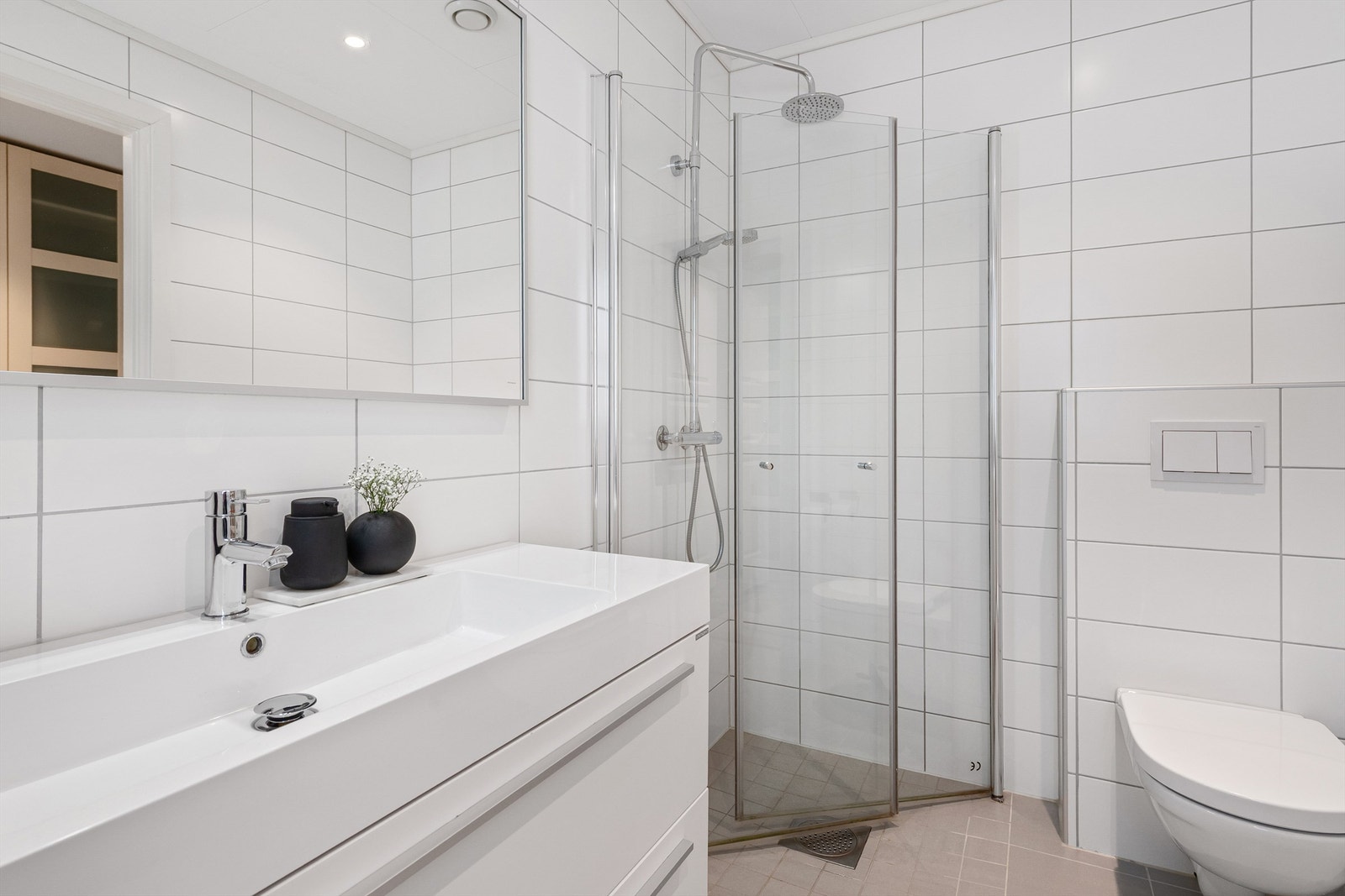 Dusjhjørne med foldbare glassvegger med vegghengt dusjarmatur. Vegghengt toalett. Galleribilde