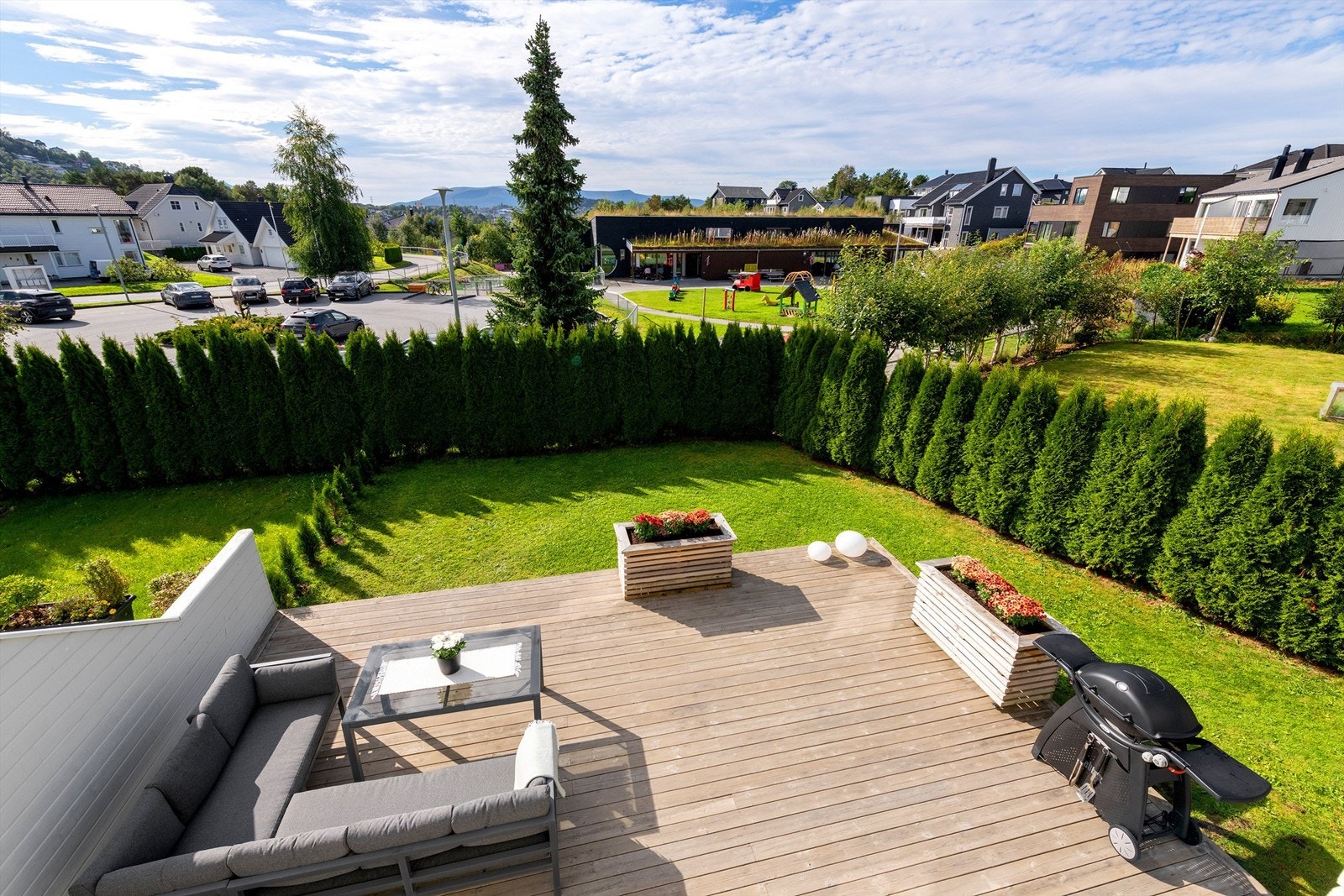 Utsikt fra veranda i 1. etasje til markterrasse og hage som er opparbeidet med plen og inngjerdet med hekk. Flott skjermet og barnevennlig uteområde Galleribilde