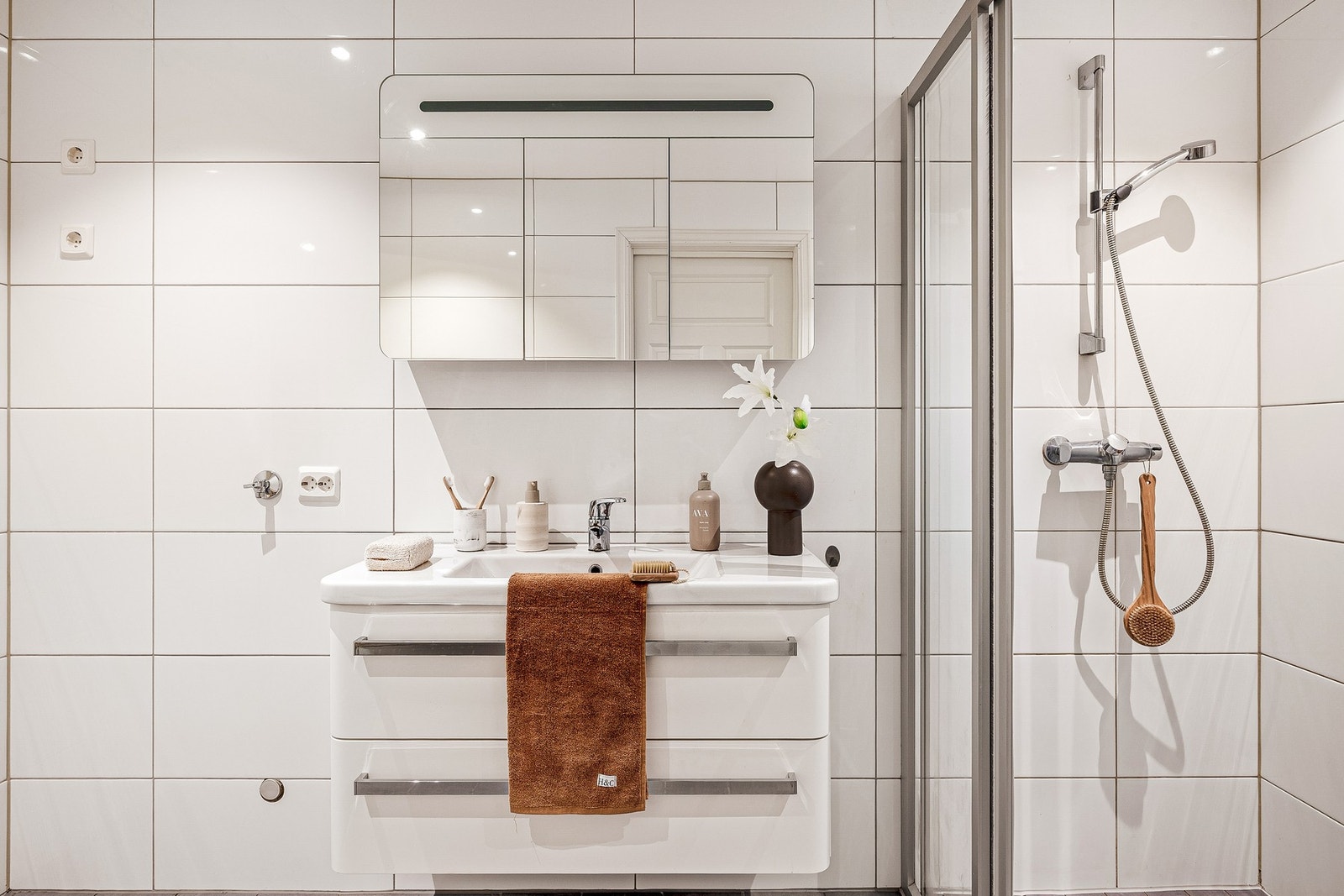 Badet er innredet med servant, skap med belysning, vegghengt toalett og dusjhjørne Galleribilde