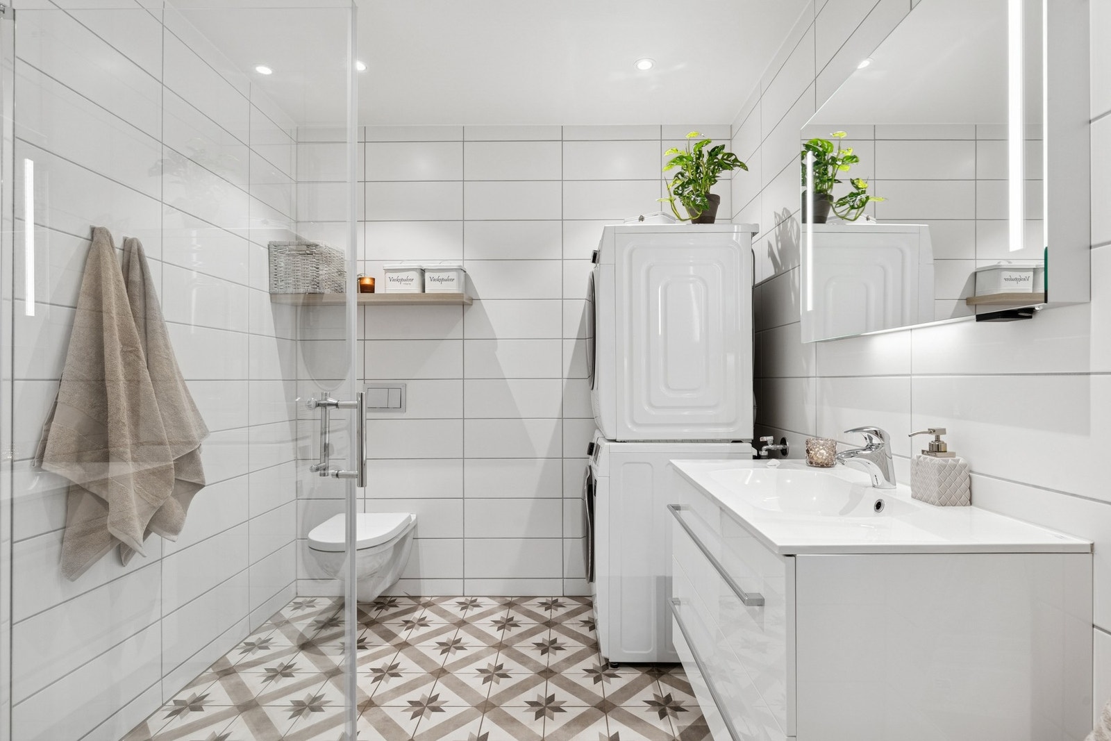 Vegghengt toalett, samt opplegg for både vaskemaskin og tørketrommel. Separat dusjhjørne og innfellbare glassdører. Himlingen er lyssatt med downlights. Galleribilde