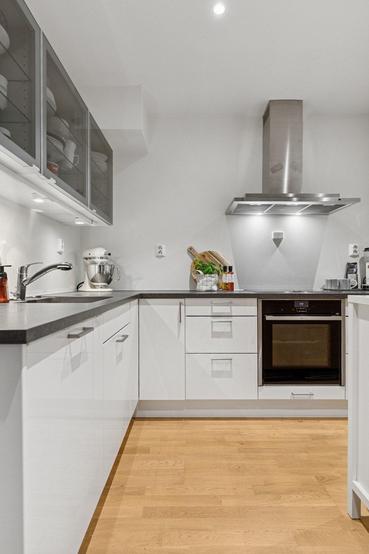 Innredning med hvite glatte fronter og laminert benkeplate. Benkeskapsbelysning og nedfelt oppvaskkum. Galleribilde