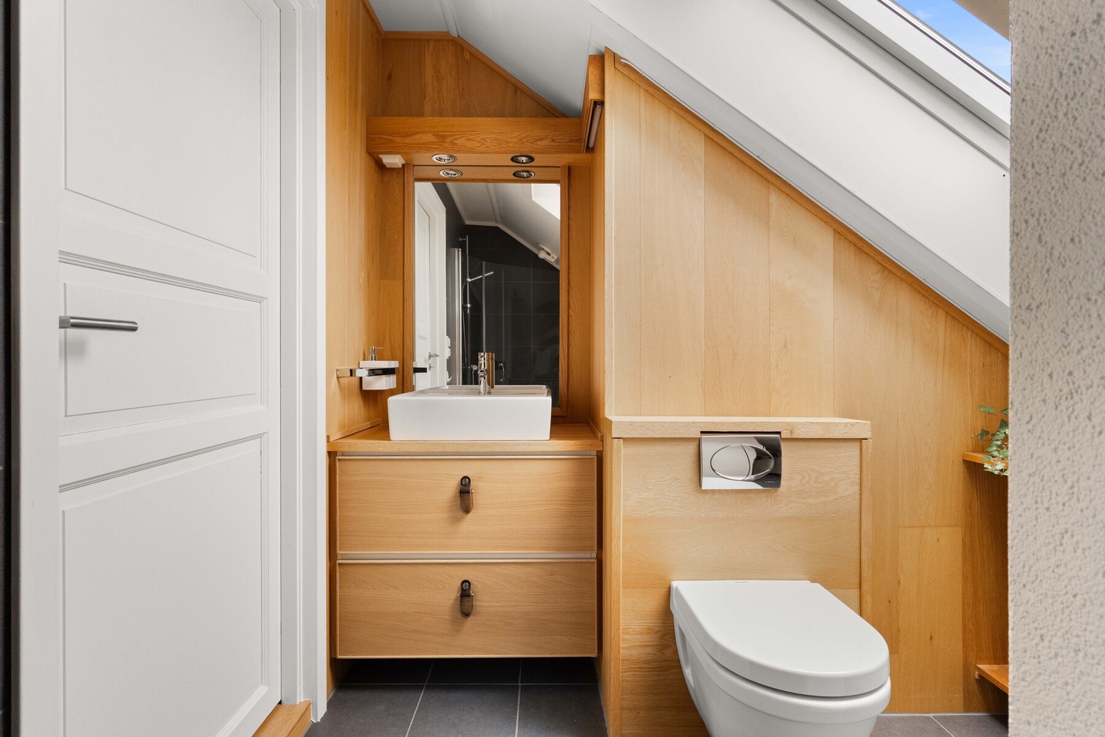 Badet er innredet med servantskap med skuffer, benkeplate i tre og ovenpåliggende servant. Galleribilde