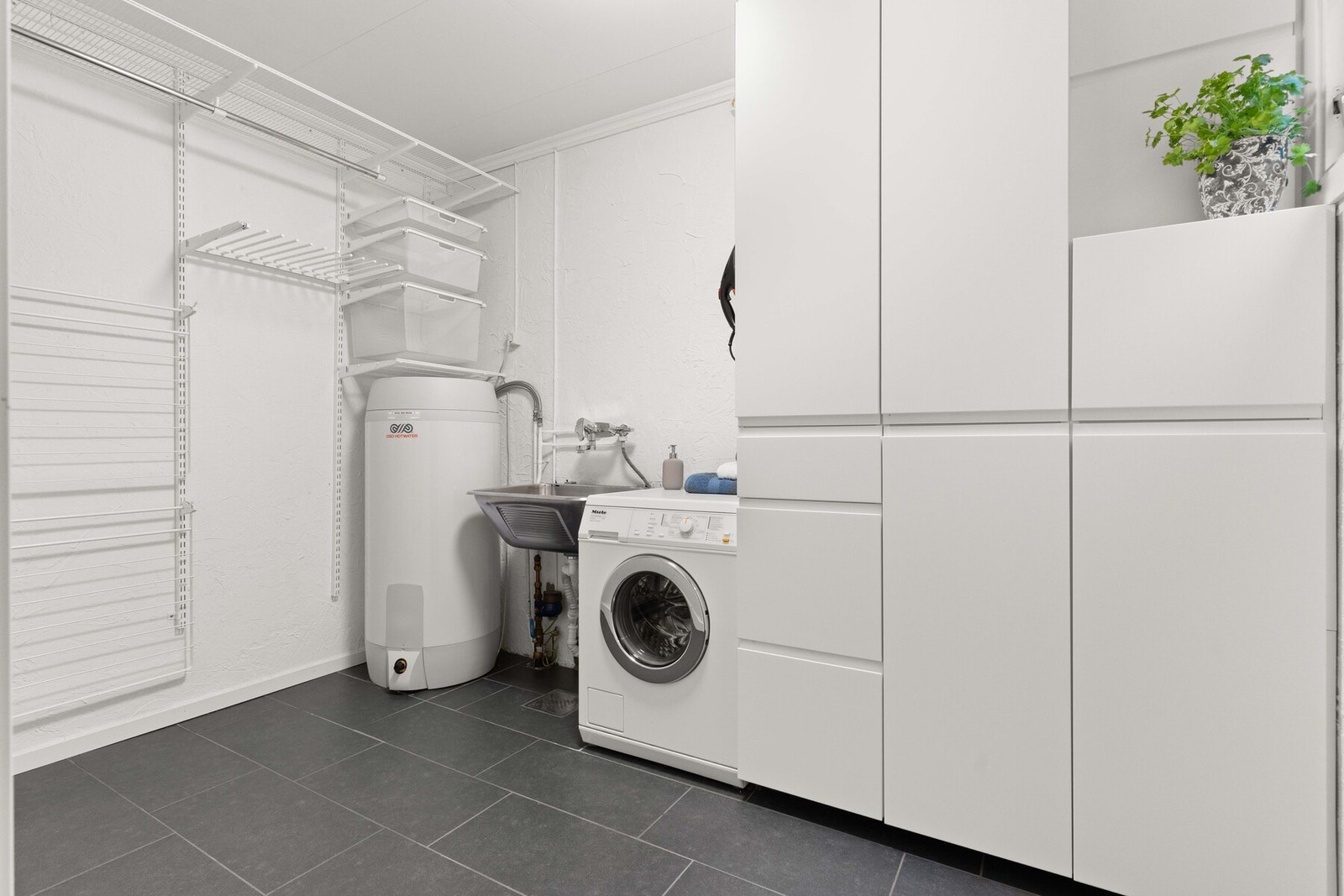 Vaskerommet er fra byggeår, med oppgraderinger utført i 2021. Gulvet er flislagt og har gulvvarme. Her er varmtvannsbereder på ca. 200 liter fra 2021, samt hovedstoppekran og vannmåler. Galleribilde