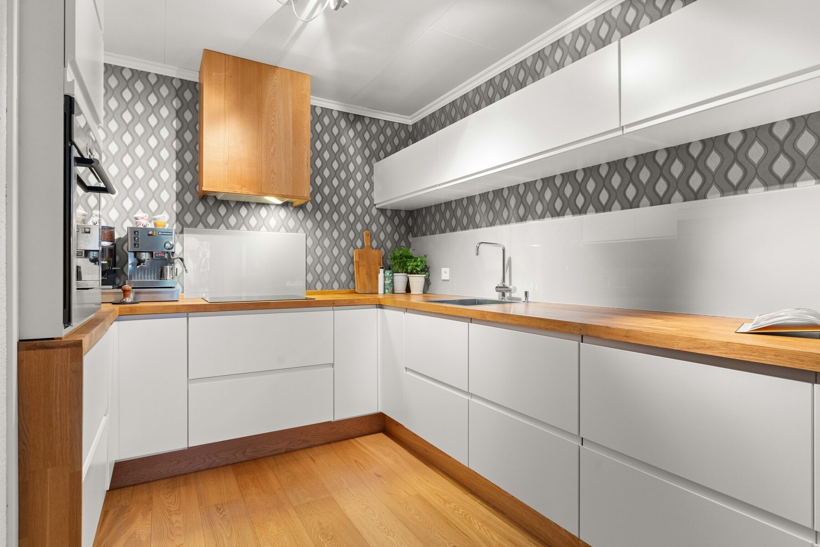 Innredningen har slette fronter og benkeplater i tre, med stedvis glassplate i våtsonene over kjøkkenbenken. Galleribilde