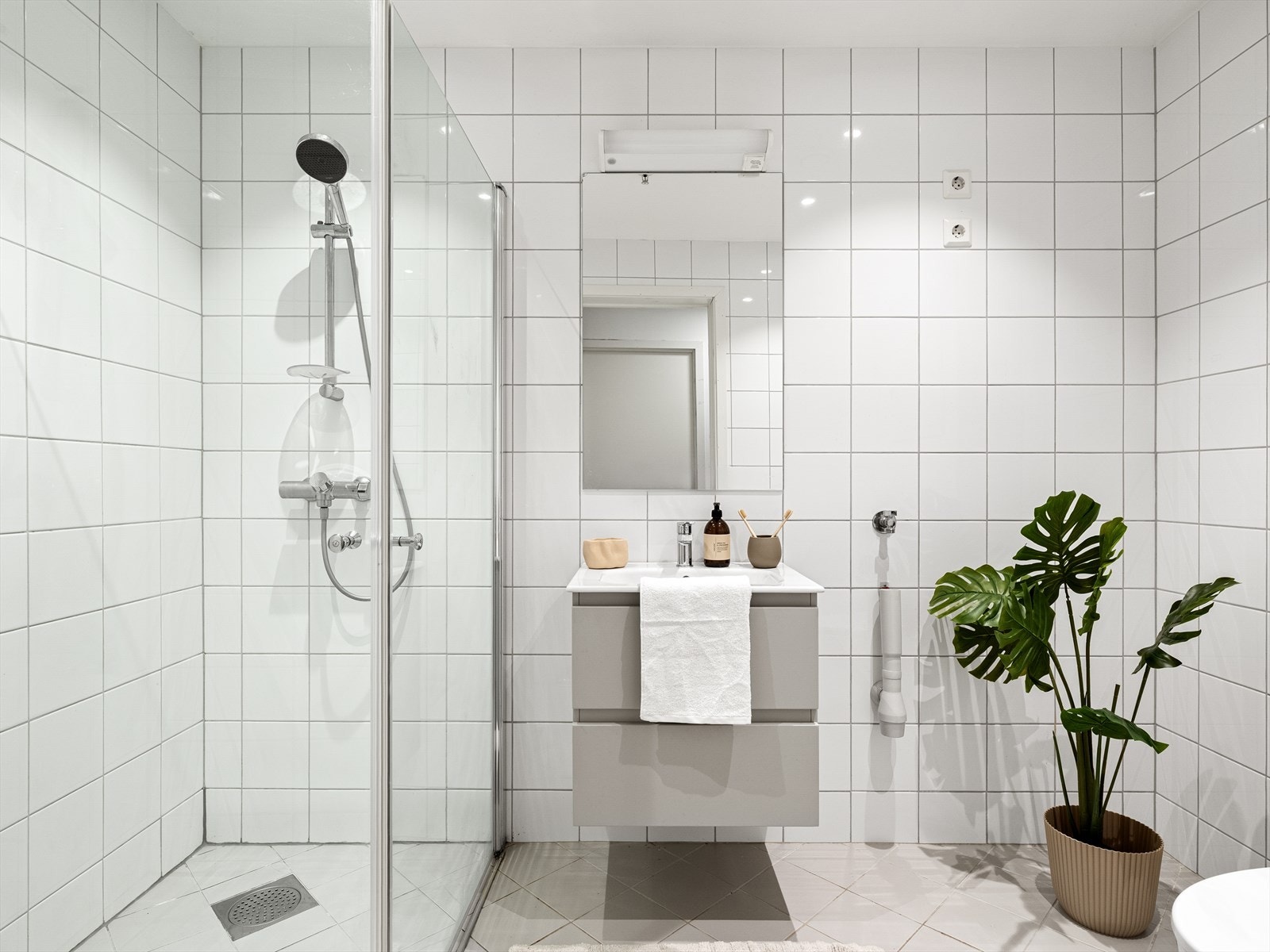 Helfliset bad med varme i gulv. Spotter i tak. Dusj med fleksible glassdører, vegghengt wc og vask i seksjon. Opplegg for vaskemaskin. Galleribilde