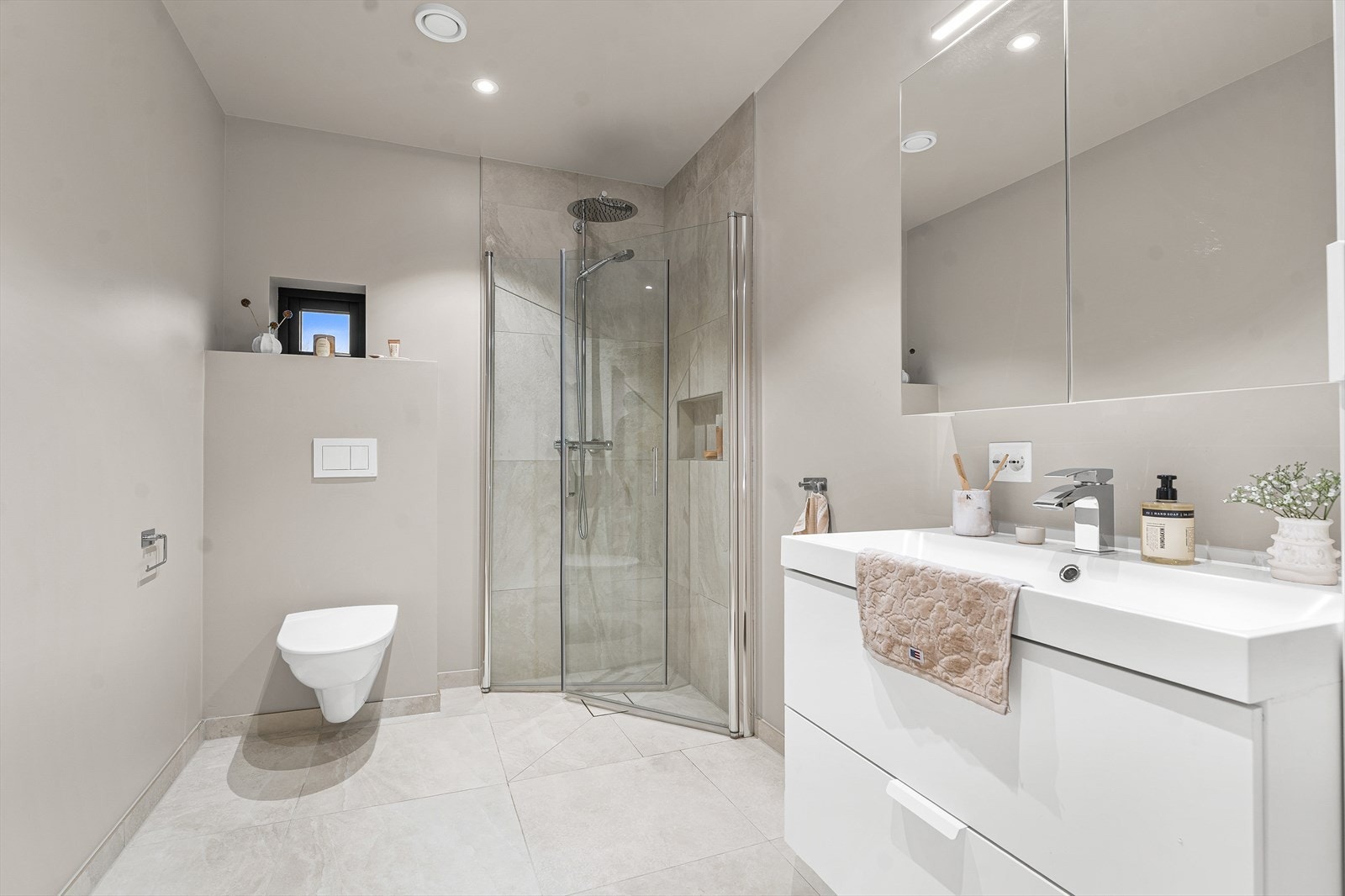 Badet er innredet med nedfelt servant, vegghengt toalett og dusjhjørne Galleribilde