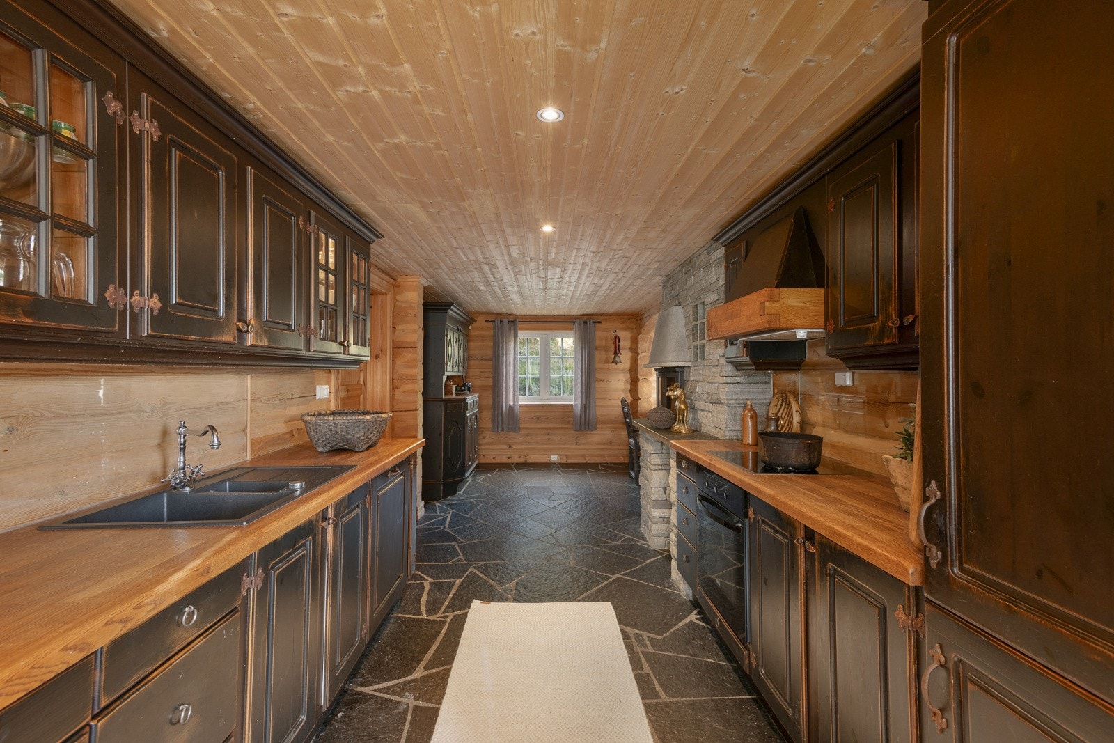 Kjøkkeninnredningen i heltre har et klassisk og solid design med sorte, profilerte fronter og heltre benkeplate med kjøkkenkum. Galleribilde