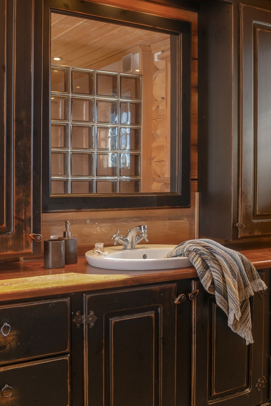 Baderomsinnredningen er utført i samme klassiske stil som kjøkkeninnredningen, med sorte, profilerte fronter og heltre benkeplate med nedfelt servant. Galleribilde