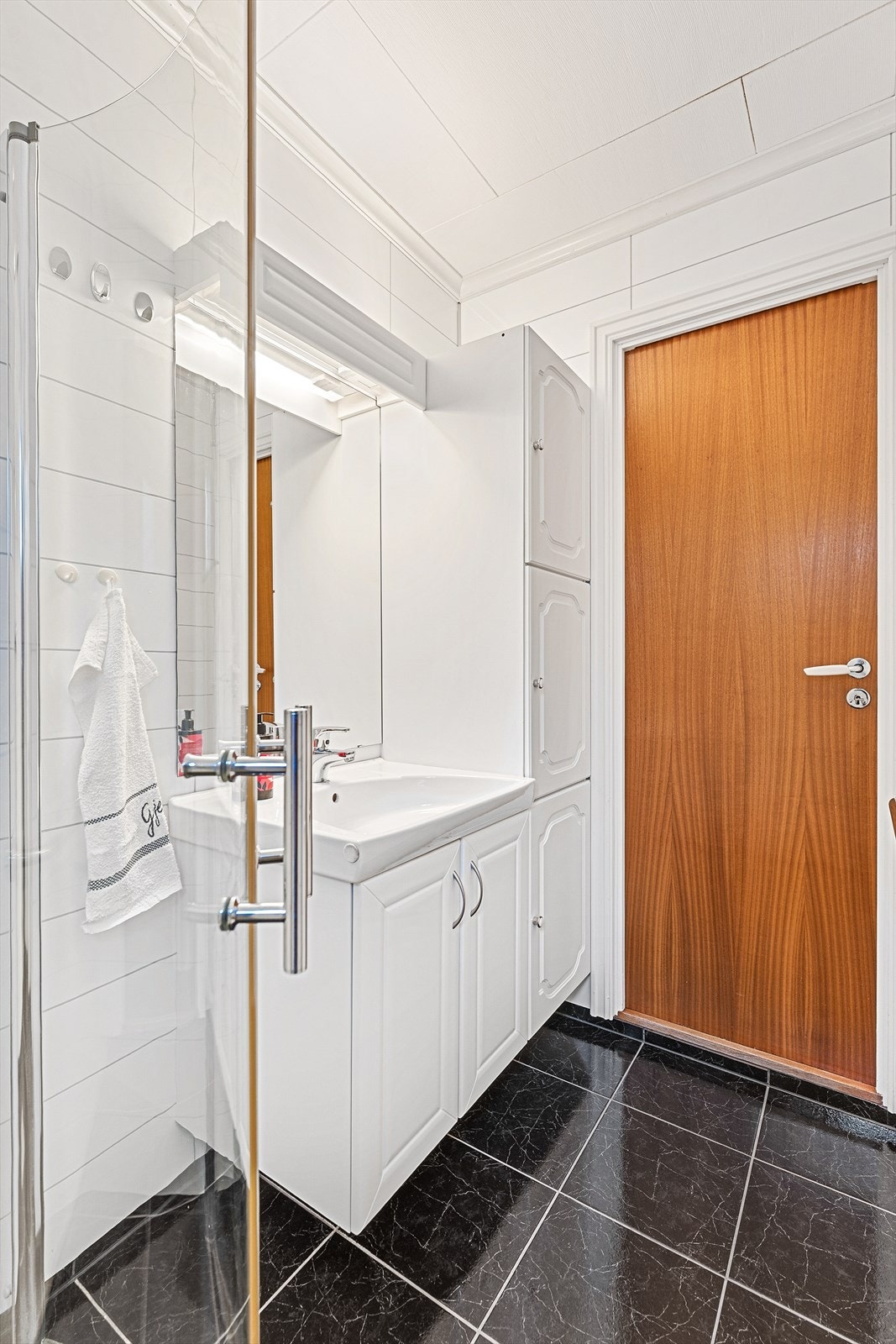 Rommet er innredet med servant med høyskap og dusjhjørne Galleribilde