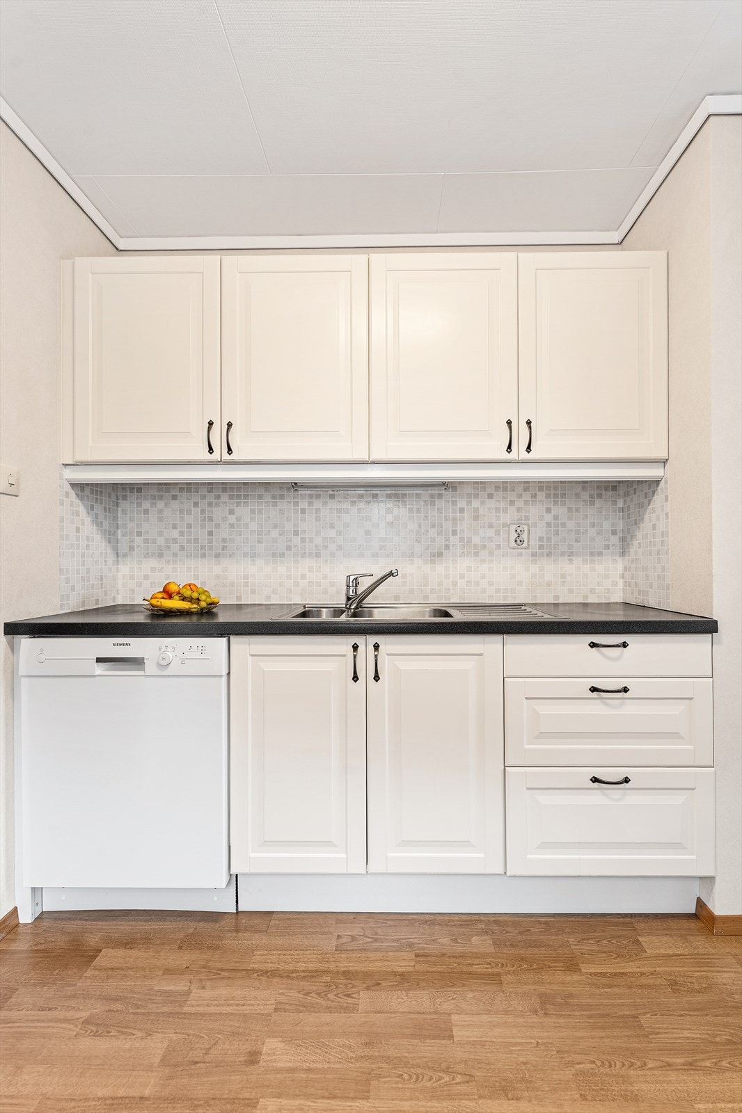 Kjøkkenet har profilerte fronter og benkeplate av laminat Galleribilde