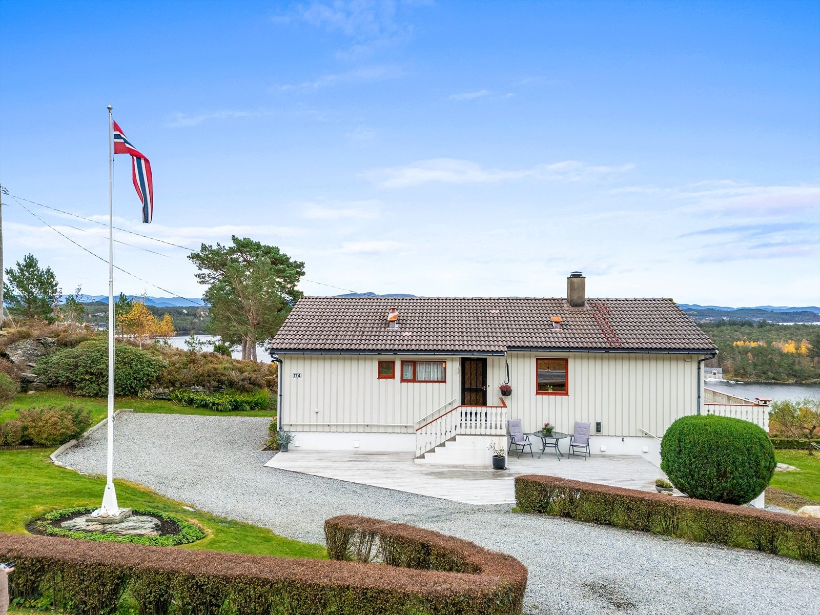 Tomten er pent opparbeidet med gruset innkjørsel, terrasse, plen og beplantning Galleribilde