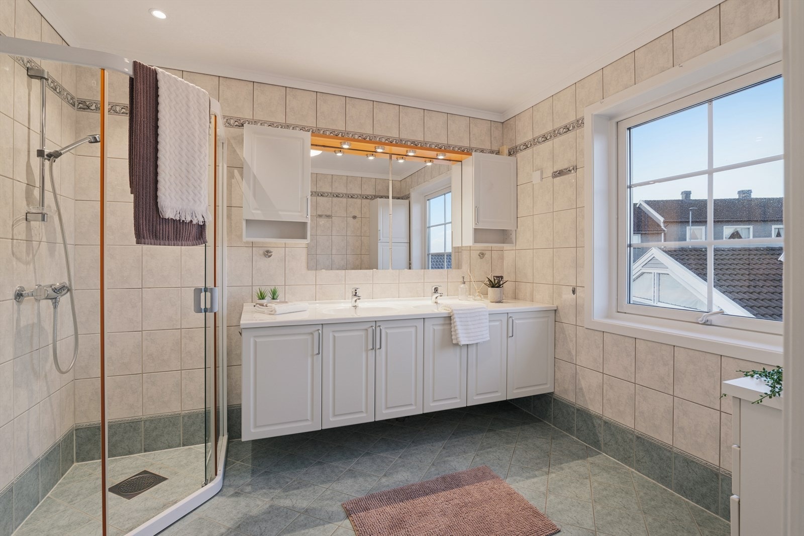 Romslig og funksjonelt baderom i 2 etasje med flislagte overflater i lyse og tidløse farger. Badet er utstyrt med dobbel servant med god skapplass, stort speil med belysning og dusjhjørne med glassdører Galleribilde