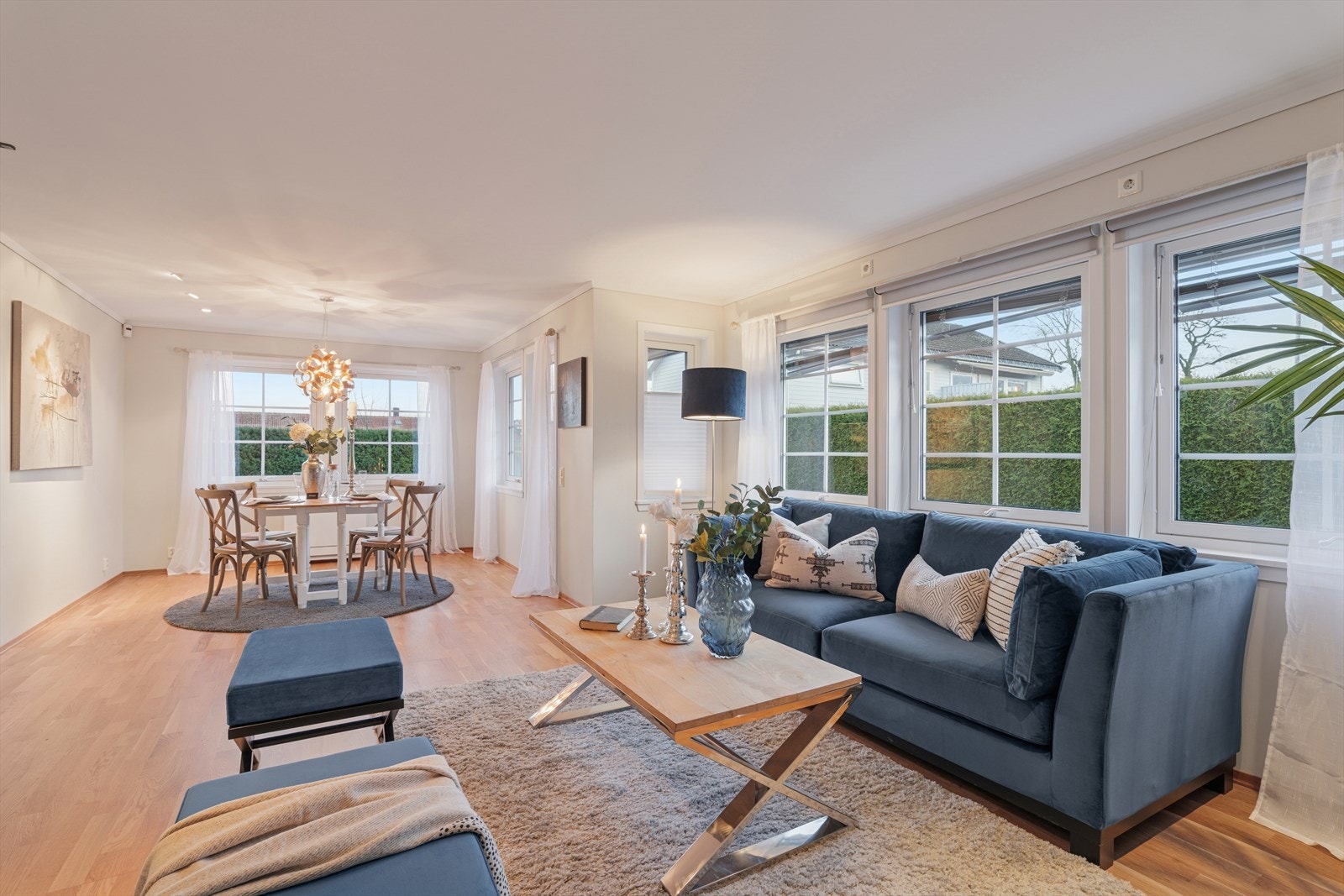 Lys og romslig stue med store vindusflater som gir rikelig med naturlig lys. Åpen løsning mot spisestue skaper en luftig atmosfære, perfekt for både hverdagsliv og sosiale sammenkomster Galleribilde