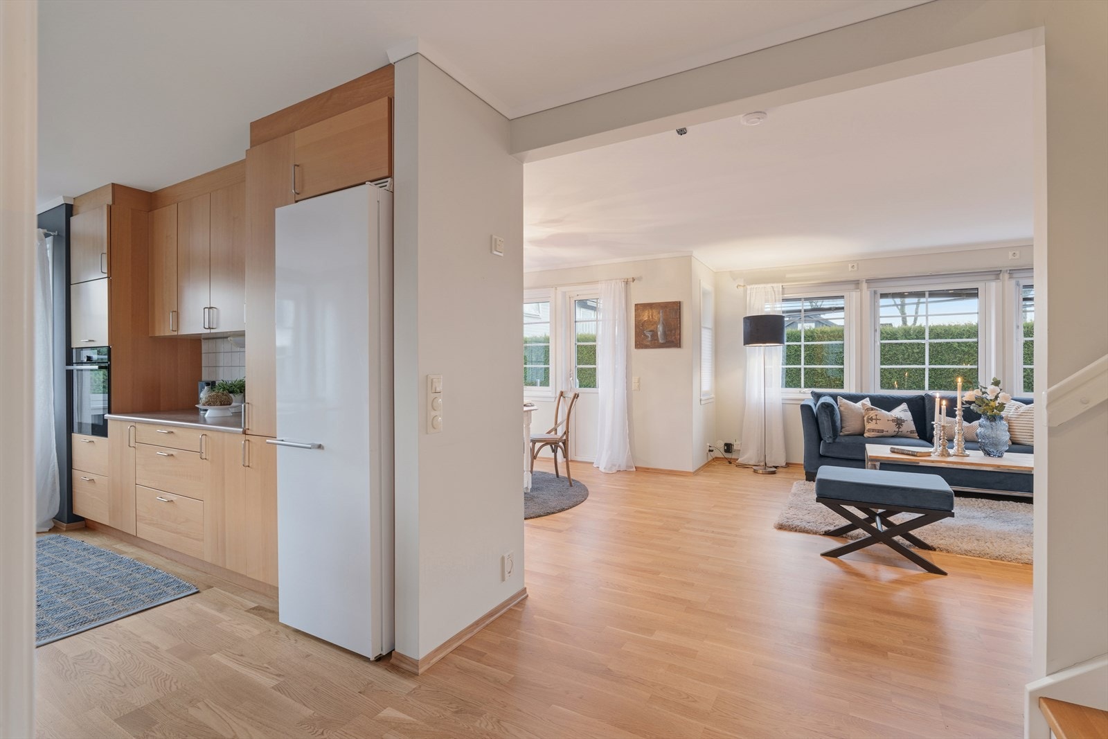 Kjøkken og stue ligger i en delvis åpen løsning som gir en fin balanse mellom sosialt samvær og praktisk funksjonalitet. Den åpne forbindelsen skaper god flyt i rommet, samtidig som kjøkkenet har sin egen sone for matlaging. Galleribilde