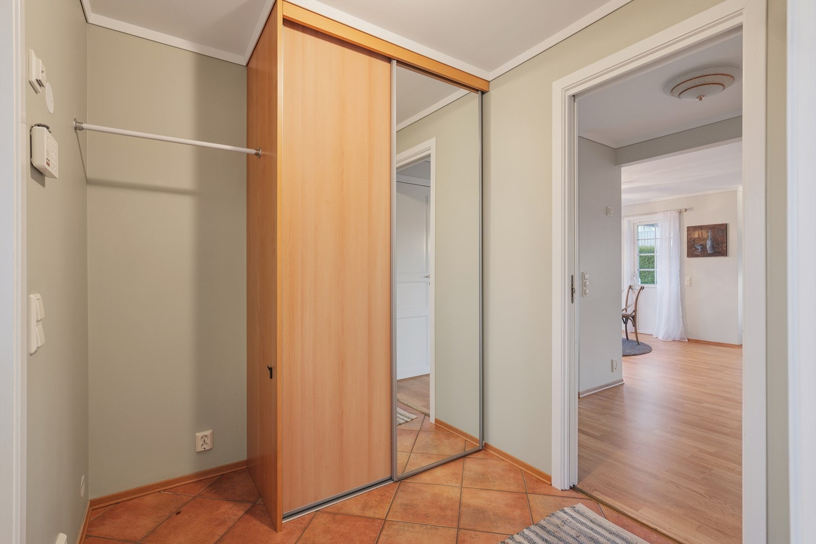 Praktisk entré med flislagt gulv og god plass til oppbevaring. Skyvedørsgarderobe med speil gir både rikelig lagringsplass og en følelse av romslighet. Galleribilde