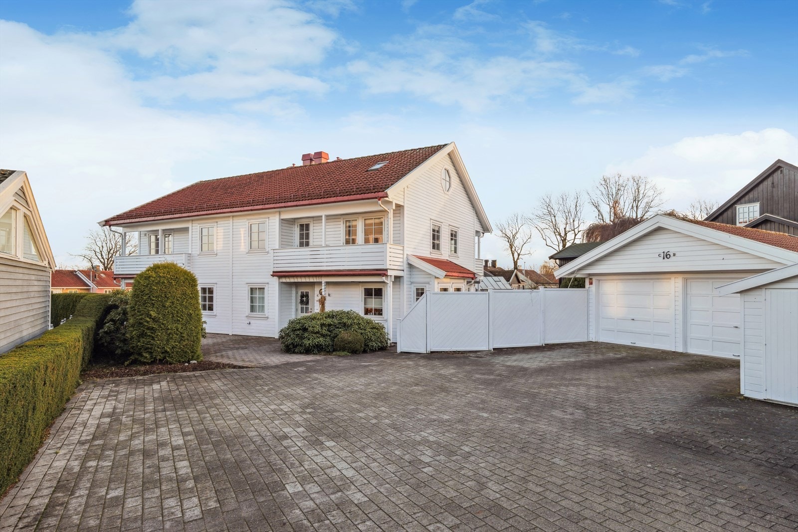 Velholdt tomannsbolig med klassisk hvit fasade, rød takstein og romslig felles gårdsplass med halvpart av dobbelgarasje Galleribilde