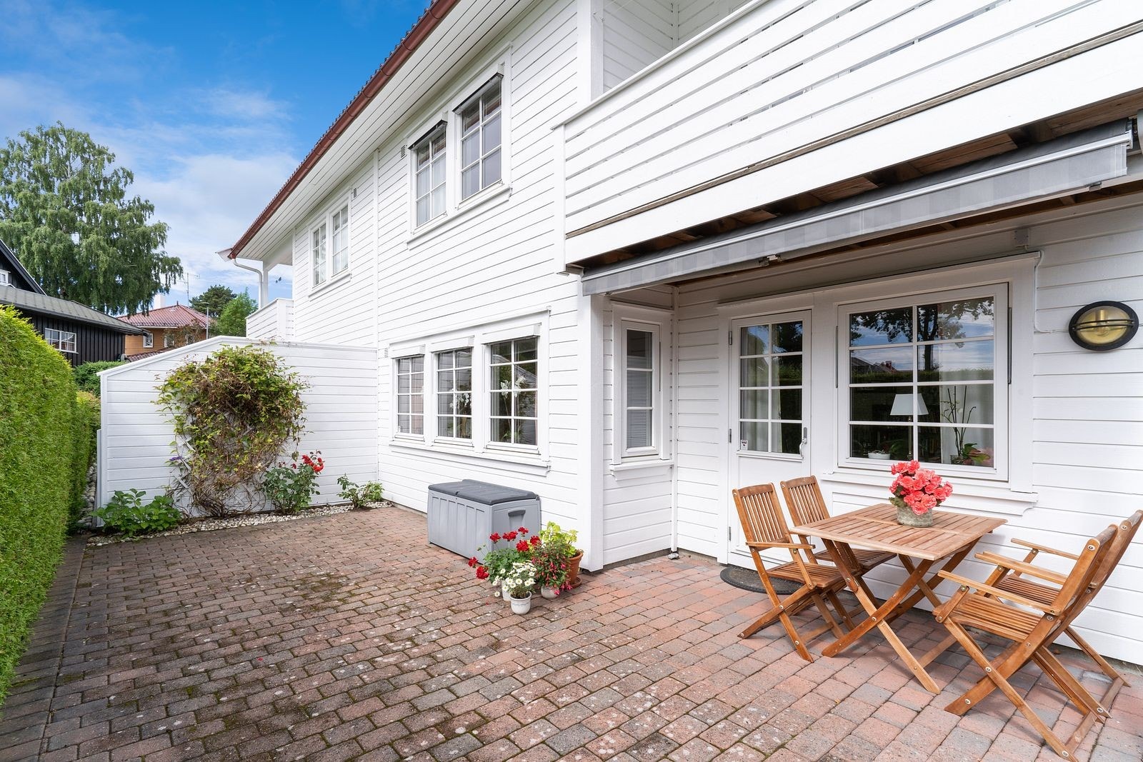 Trivelig og skjermet uteplass med belegningsstein, god plass til sittegruppe og frodige innslag av grønt. Perfekt for hyggelige måltider og avslapning i rolige omgivelser Galleribilde