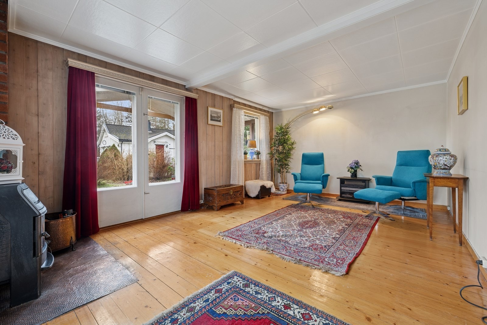 En lys og luftig stue med peis, store vindusflater som slipper inn godt med naturlig lys, og fleksible møbleringsmuligheter som gjør rommet ideelt som TV-stue og samlingspunk Galleribilde