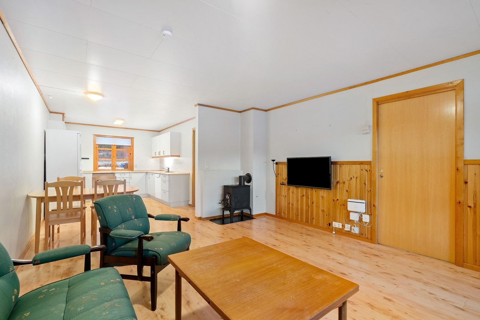 Det er åpen løsning mellom kjøkken og stue, og vedovn gir effektiv oppvarming av rommene. Galleribilde