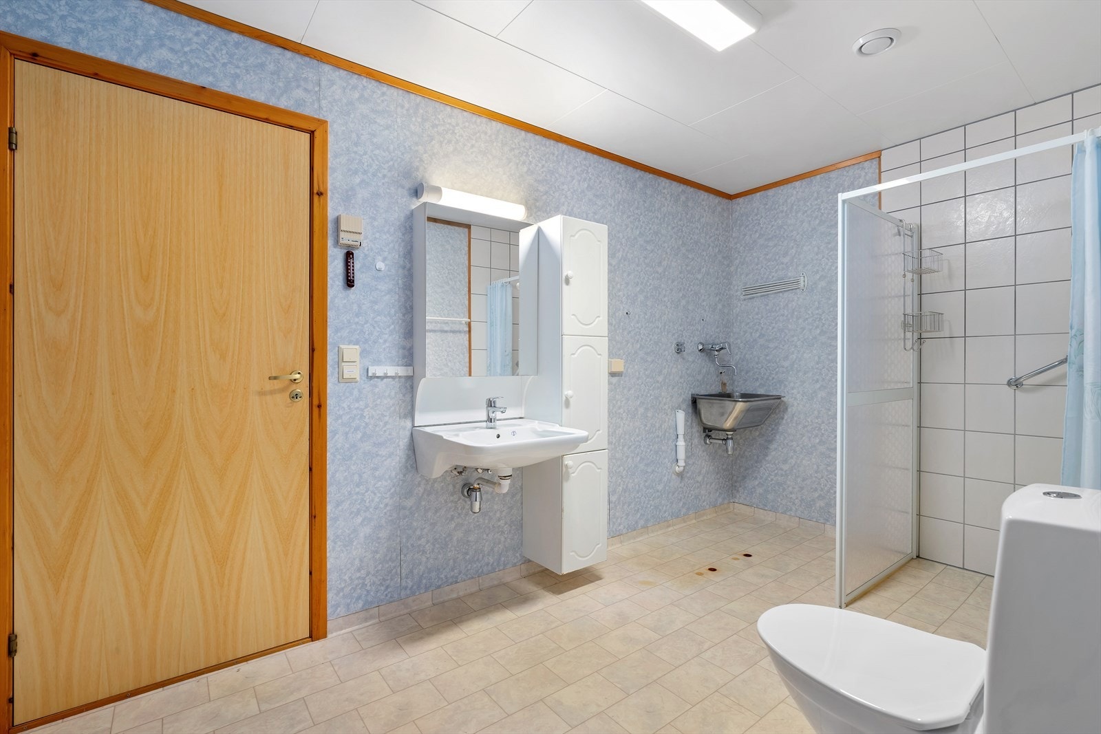 Vegghengt servant med tilhørende speilskap gir funksjonell oppbevaringsplass. Opplegg til vaskemaskin i hjørnet Galleribilde