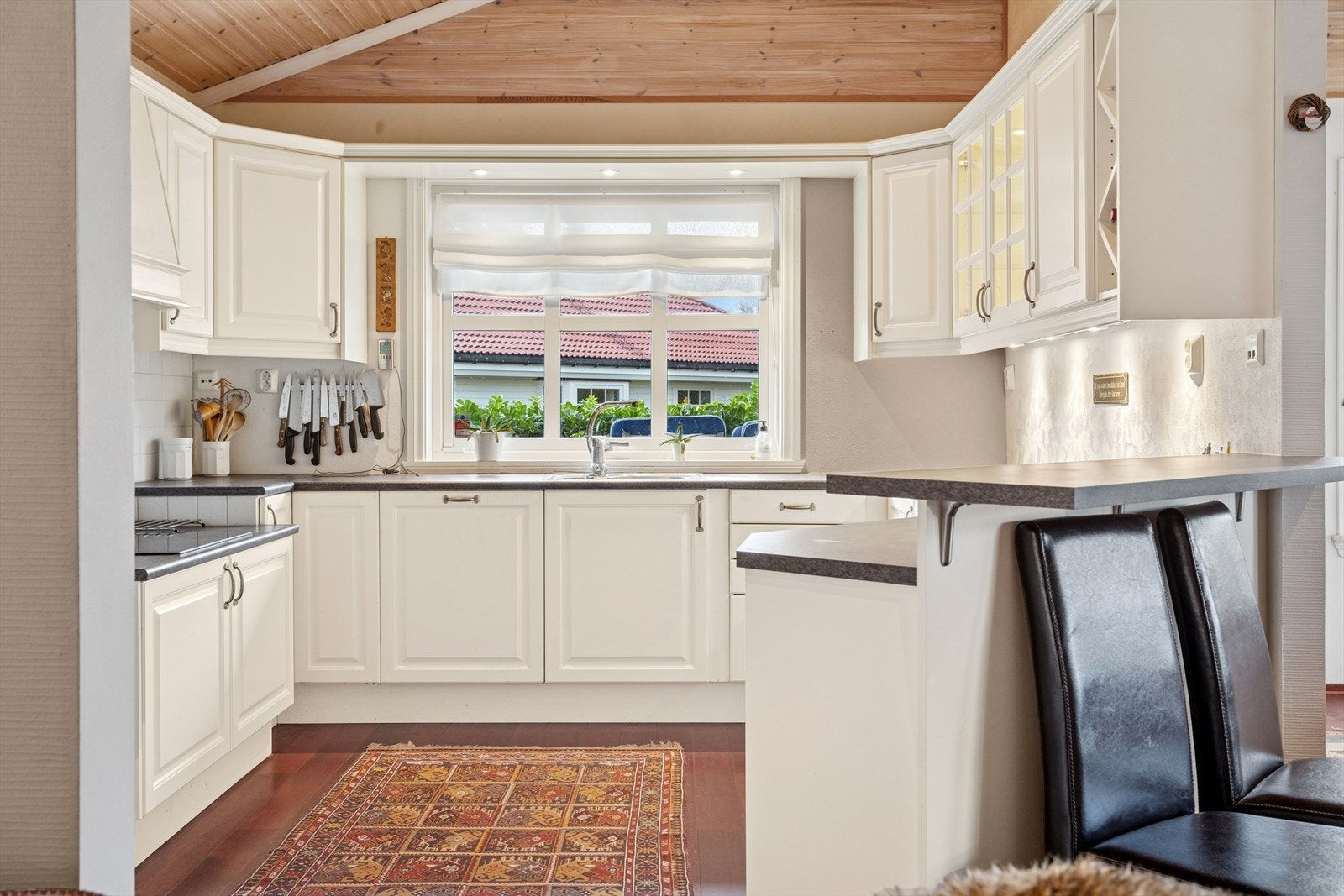 Lyst og innbydende kjøkken med stort vindu som gir rikelig dagslys og en luftig atmosfære. Galleribilde