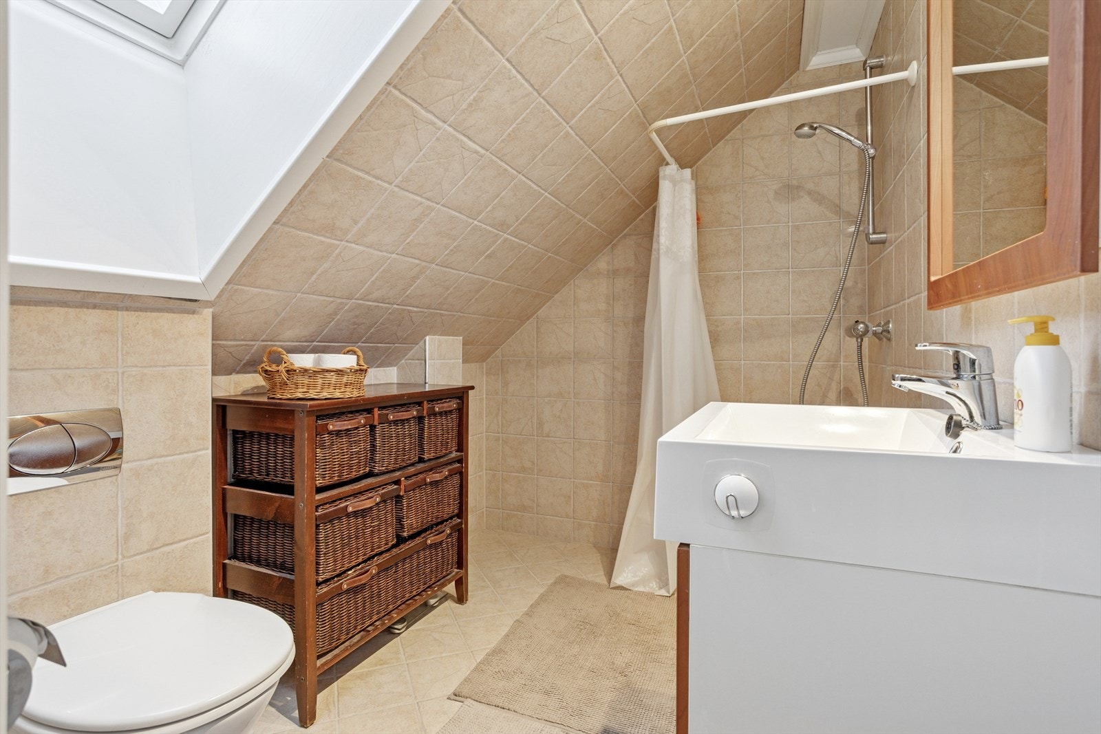 Badet er utstyrt med dusj, servant med innredning og vegghengt toalett, samt varmekabler i gulvet. Galleribilde