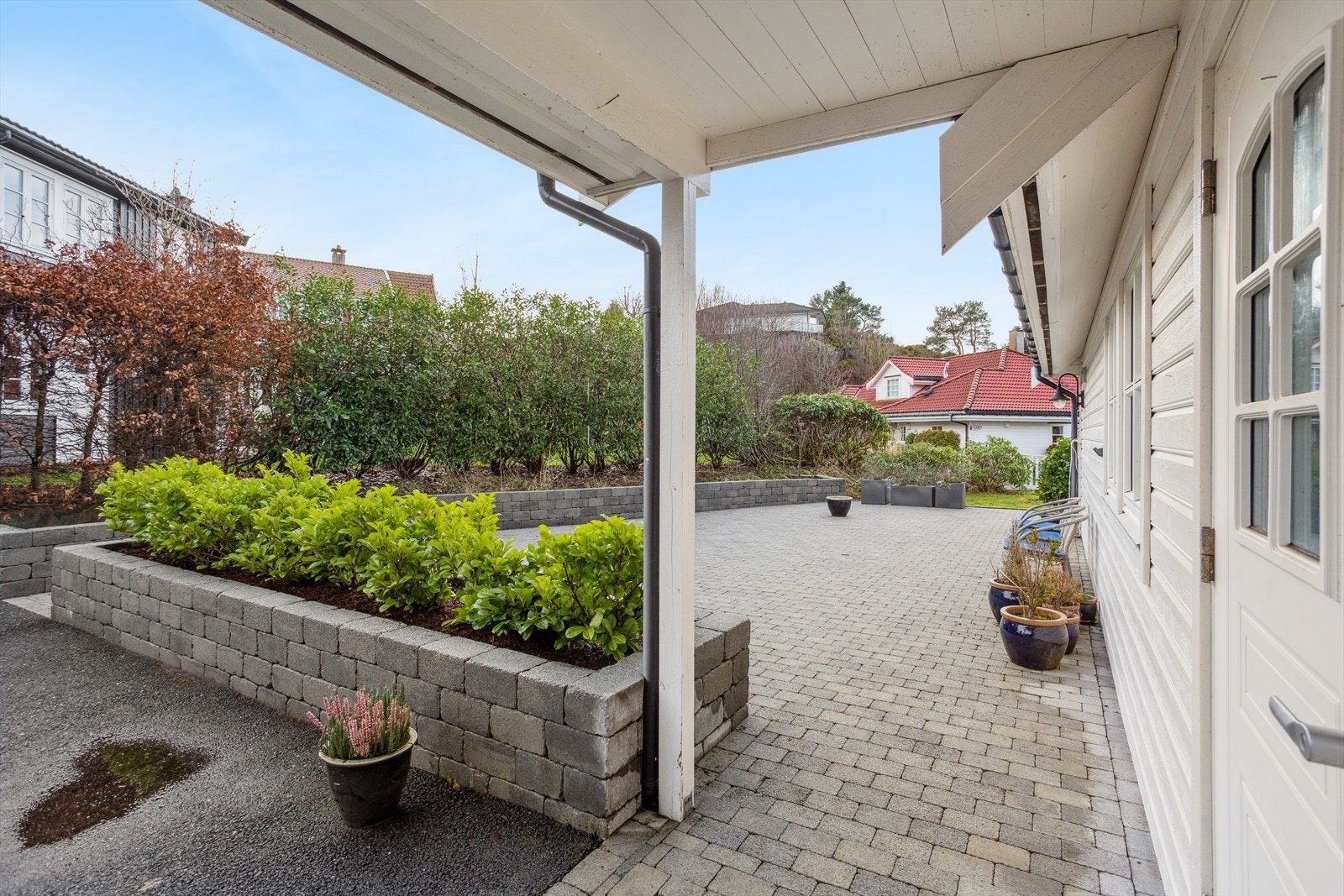 Delvis overbygget inngangsparti med stilrent tak og romslig gårdsplass - gir både beskyttelse og et innbydende førsteinntrykk. Galleribilde