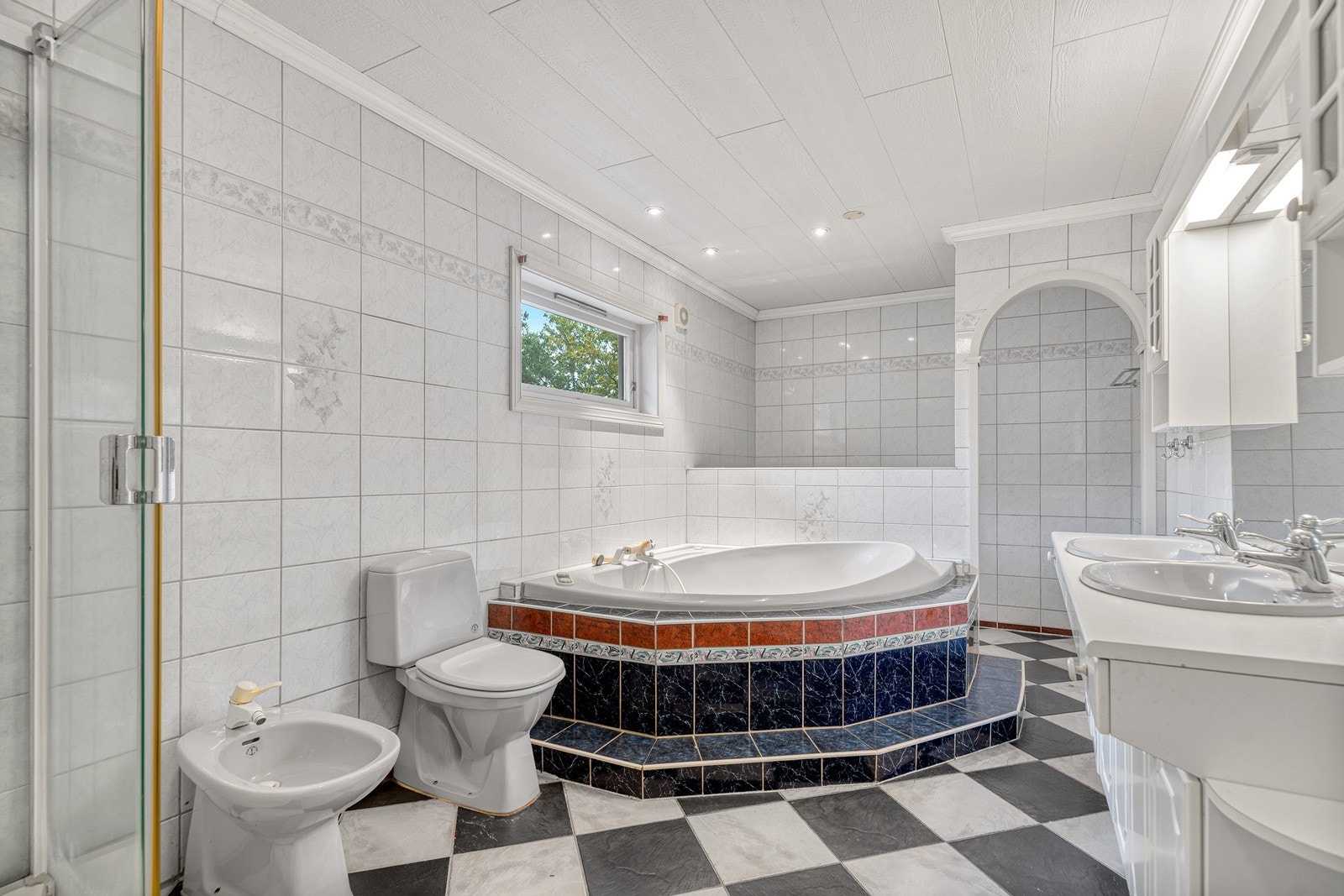 Flott bad med flislagte overflater og lekkert badekar Galleribilde