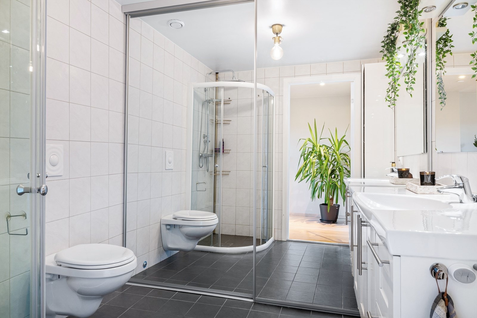 Badet er helfliset og fremstår som romslig og funksjonelt. Her finner du opphengt servant med underskap, vegghengt toalett og dusjløsning. Galleribilde