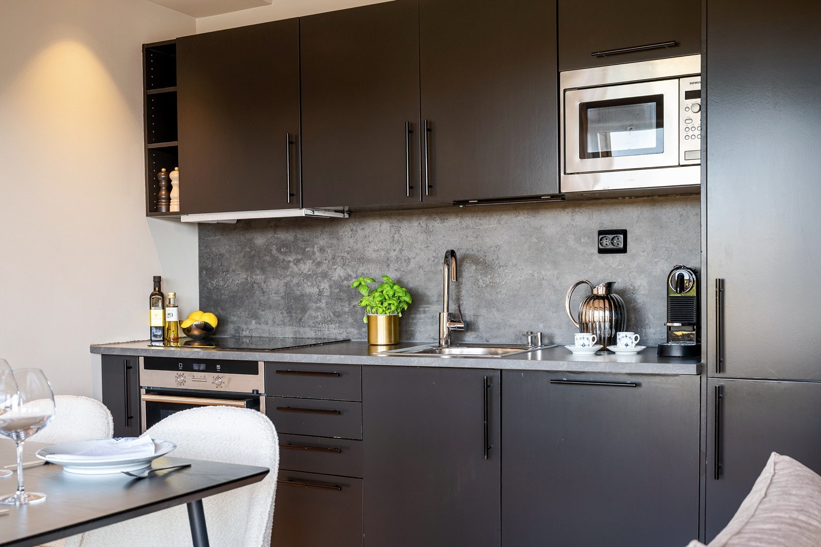 Tidløst Norema kjøkken med mørke fronter, integrerte hvitevarer og nylig oppdaterte detaljer. Galleribilde