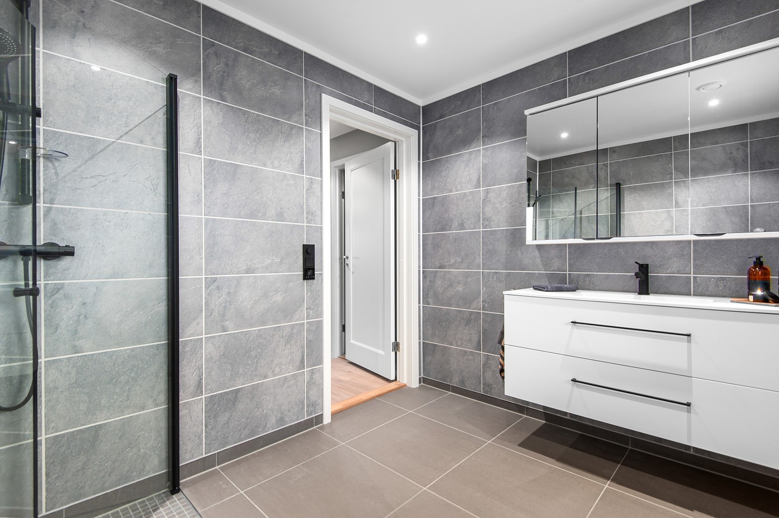 Badet/vaskerommet er utstyrt med dusjhjørne, vegghengt wc, baderomsinnredning og opplegg for vaskemaskin Galleribilde