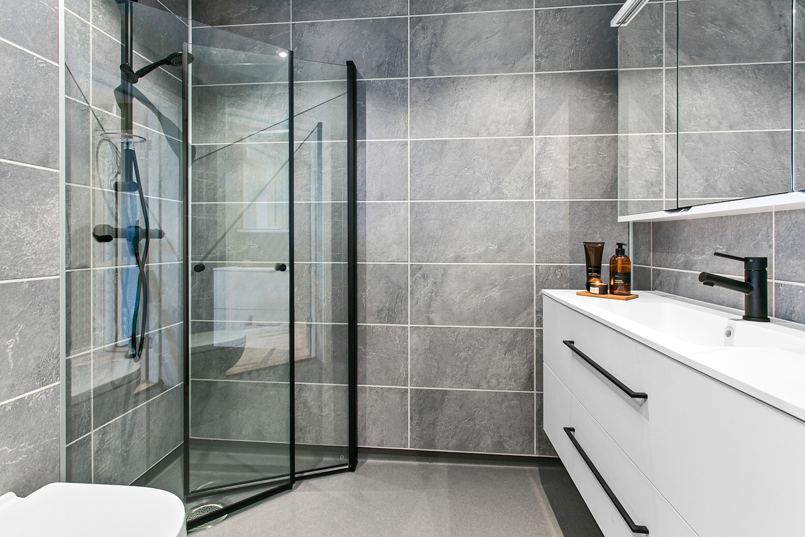 Boligen har 1 bad i hver etasje. Dette badet ligger i hovedetasjen og består av dusjhjørne, baderomsinnredning og vegghengt wc Galleribilde