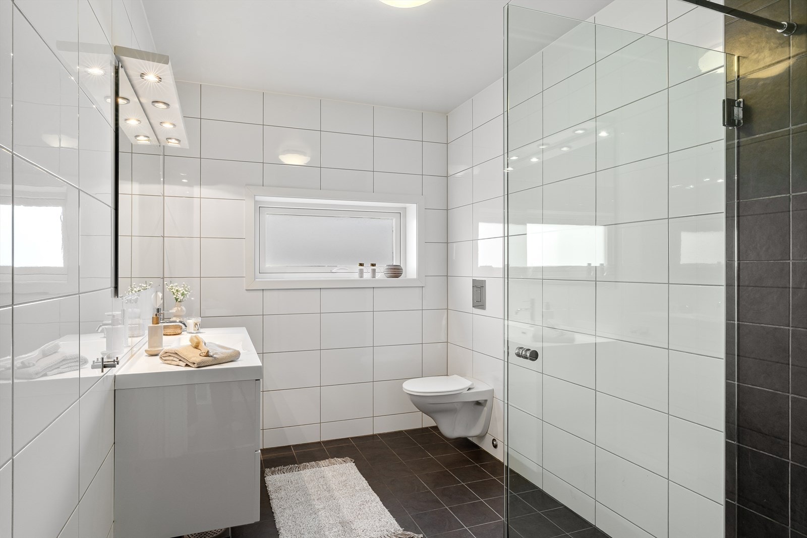 Helfliset bad som inneholder vegghengt wc, dusjhjørne, pen baderomsinnredning og varme i gulv. Galleribilde