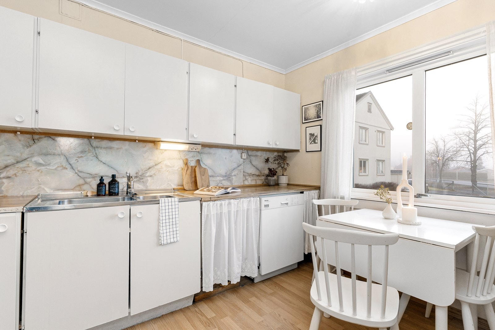 Klassisk, eldre kjøkkeninnredning med glatte fronter og laminert benkeplate. Galleribilde