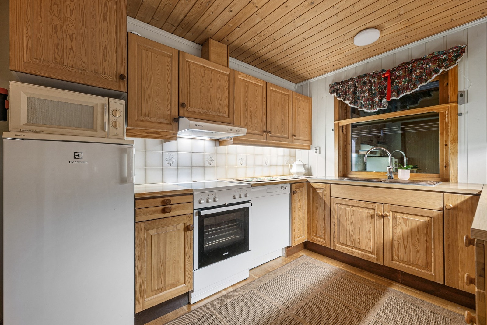 Parkett på gulv, flis på vegg over benkeplate, malt overflate og malt panel på vegger. Panel i himling. Galleribilde