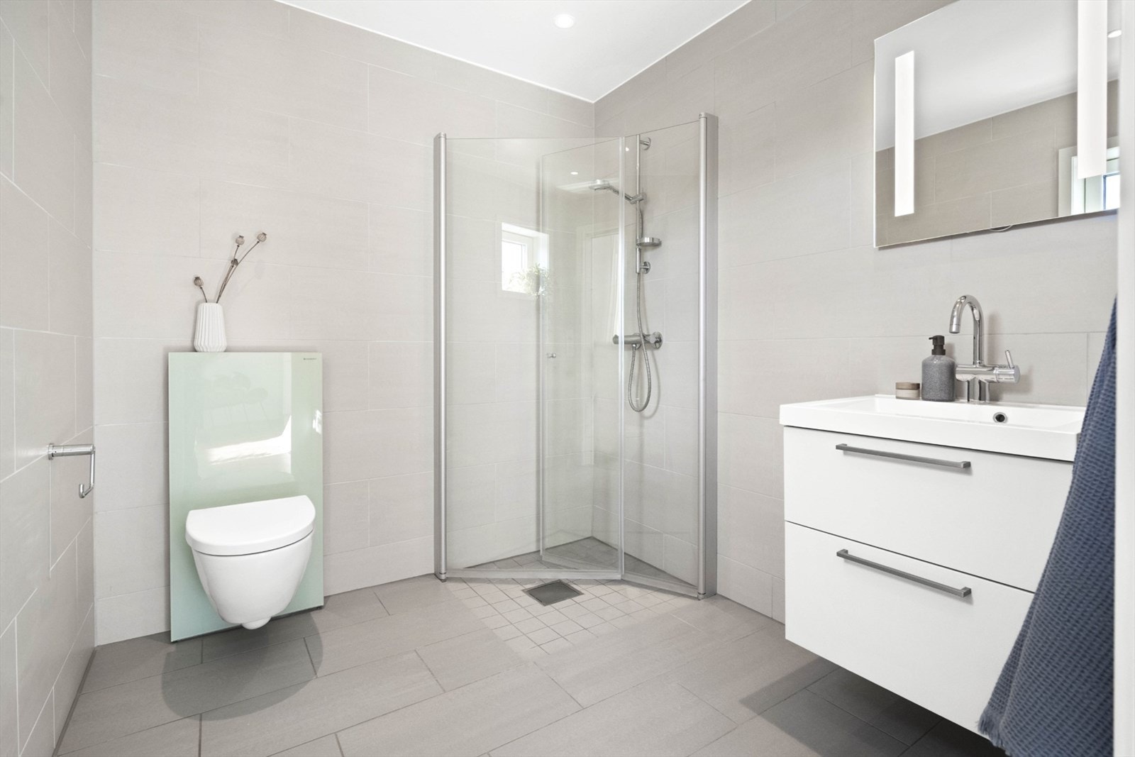 Badet tilhører hovedsoverommet. Lyse fliser med vannbåren varme i gulvet. Dusj med innfellbare dører. Galleribilde