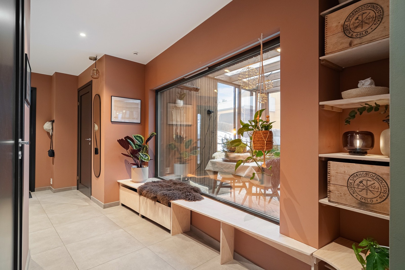 Plassbygde hyller og praktisk sittebenk ved stort vindu i entréen. Galleribilde