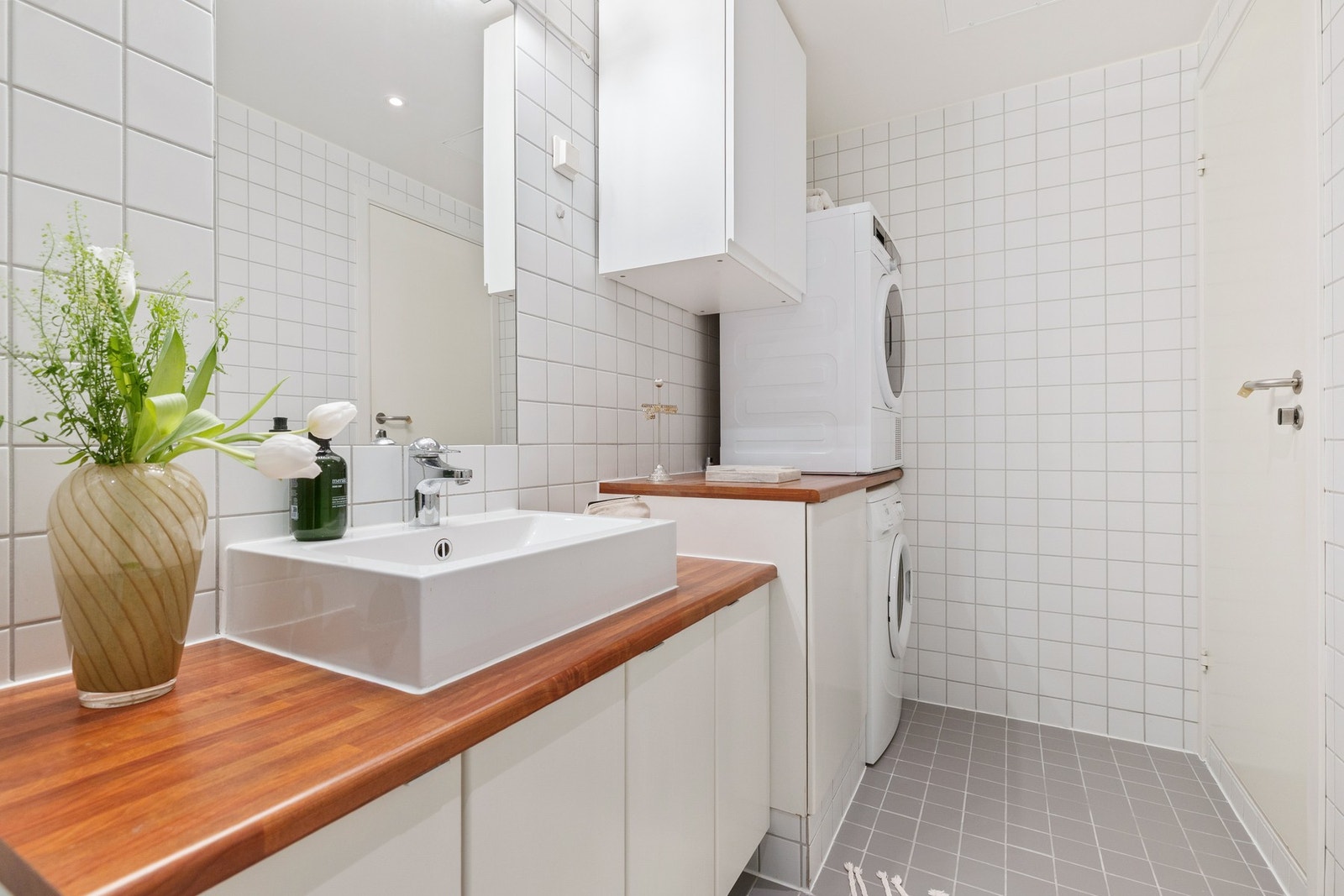 Baderomsinnredning fra Sigdal med benkeplate i laminat, skap, toppmontert servant, speil med belysning, WC og dusjhjørne. Galleribilde