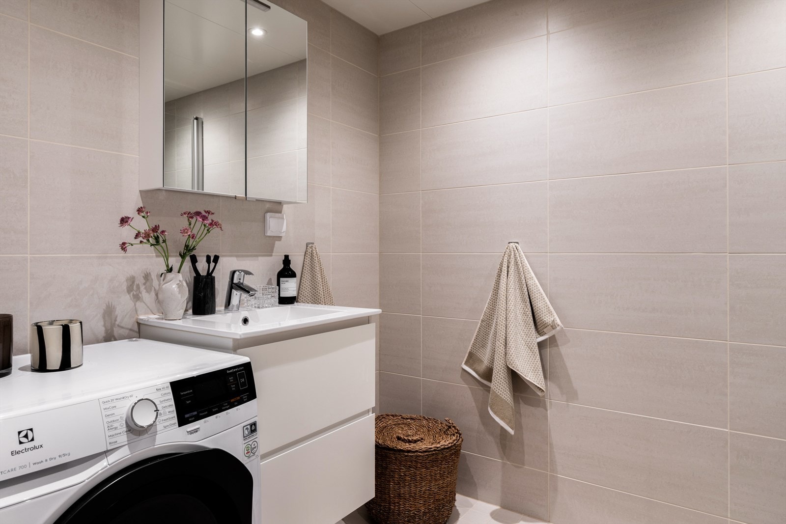 Badet har stilren baderomsinnredning med underskuffer og opplegg for vaskemaskin. Galleribilde