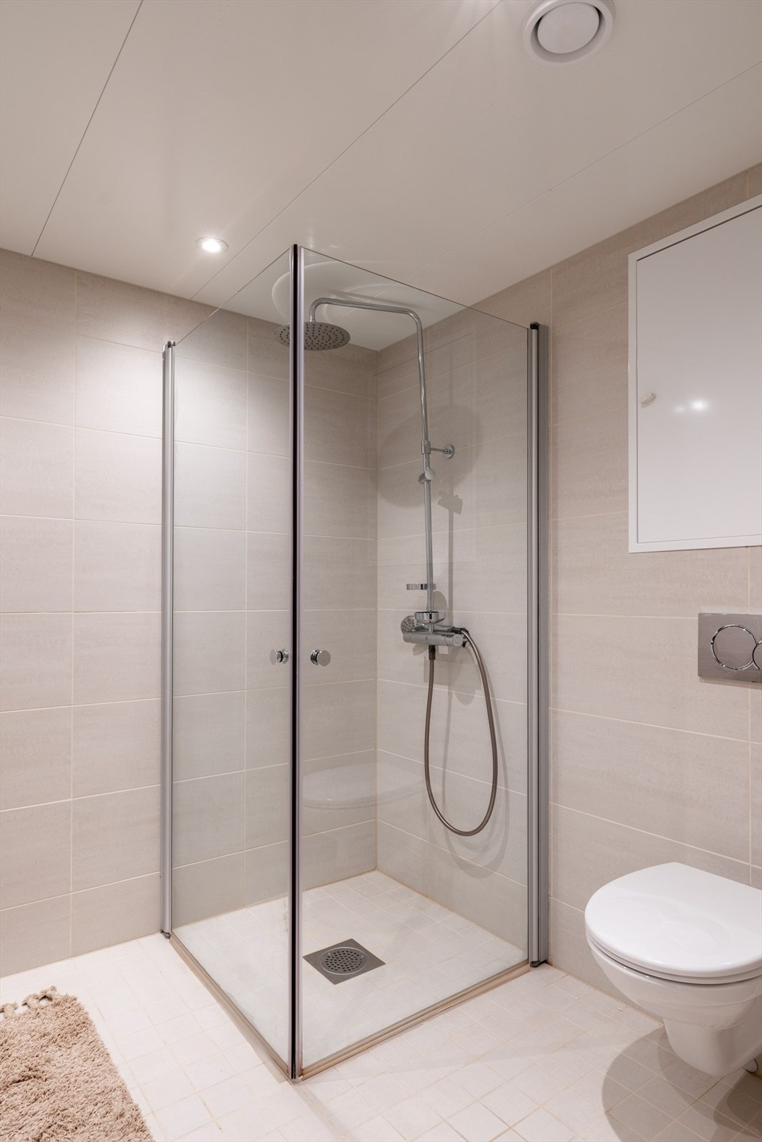 Videre er det en romslig dusjnisje bak innfellbare dusjdører, samt vegghengt toalett. Galleribilde