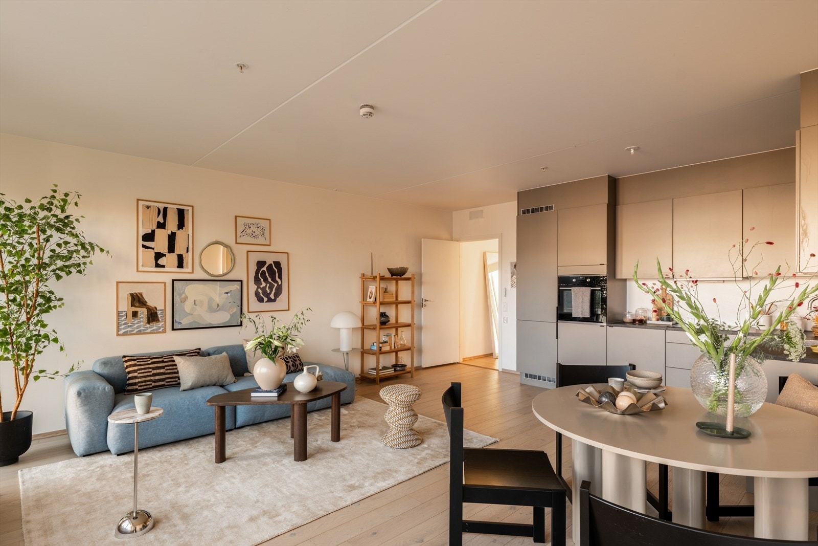 Den åpne løsningen mellom kjøkken og stue gir en naturlig soneinndeling, hvor kjøkkenet har en stilren innredning med gode oppbevarings- og arbeidsflater. Galleribilde