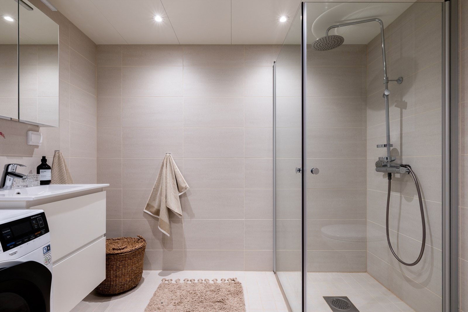 Hovedbadet fremstår moderne og delikat med lyse, tidløse fliser og downlights i himling. Galleribilde